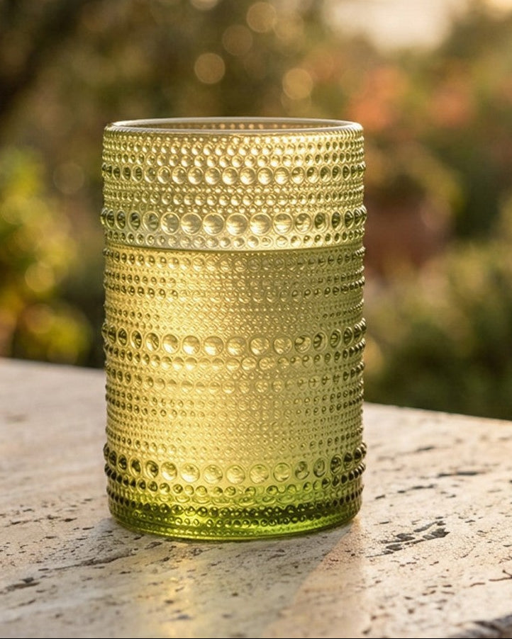 Set of green textured glass tumblers on a wooden surface with a blurred background
