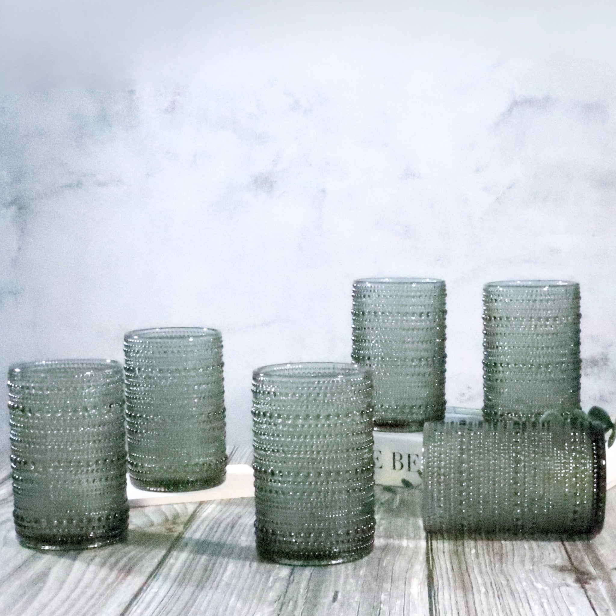 Set of hobnail jupiter bead glass grey tumblers on a wooden surface with a marble background