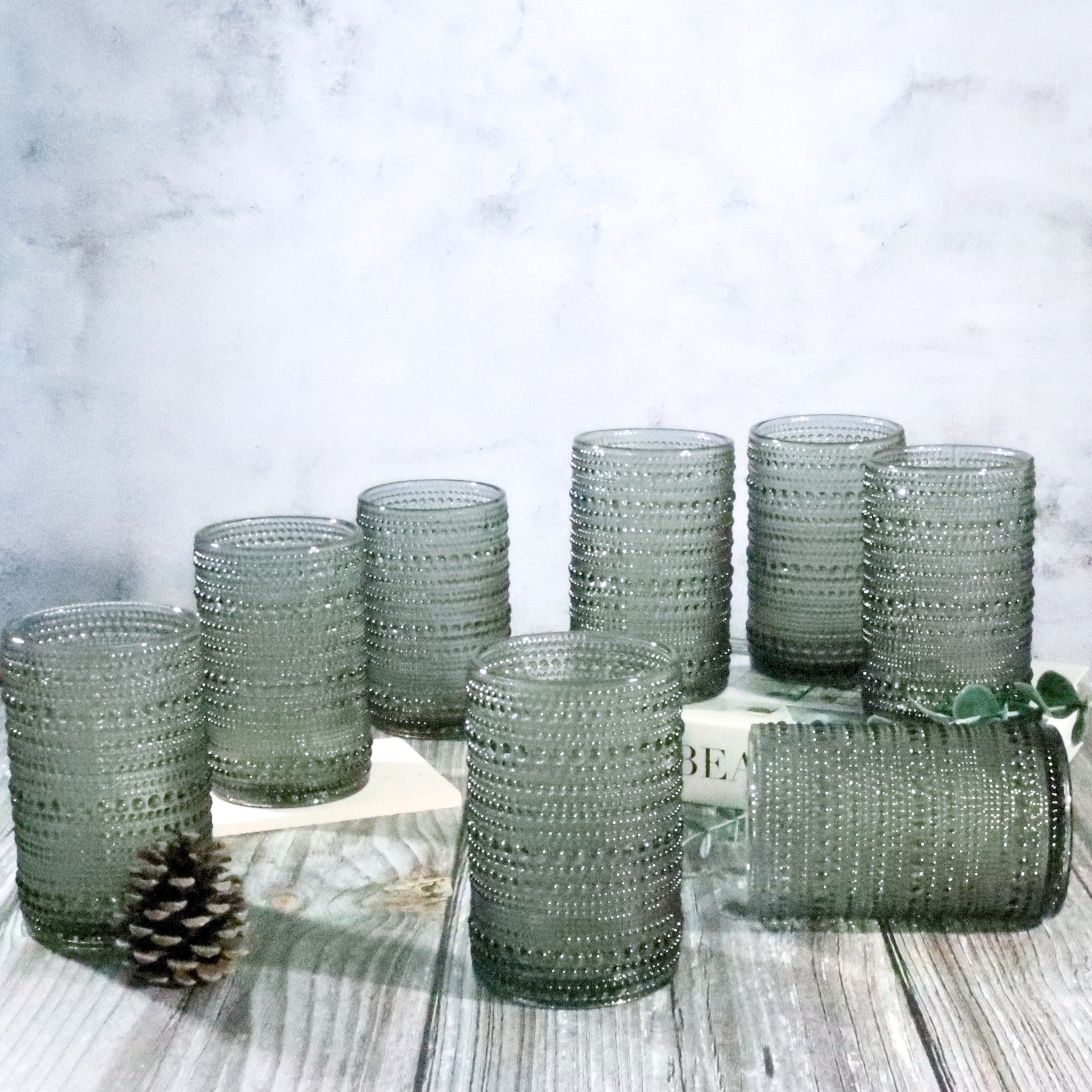 Grey Set of hobnail bead glass tumblers on a wooden surface with a light background