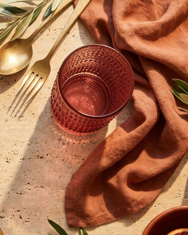 Set of purple textured glass tumblers on a white surface with decorative elements.