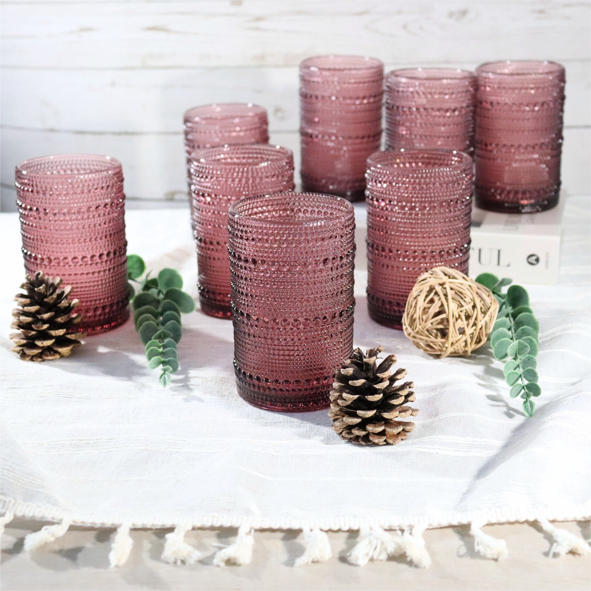 Set of purple textured glass tumblers on a white surface with decorative elements.