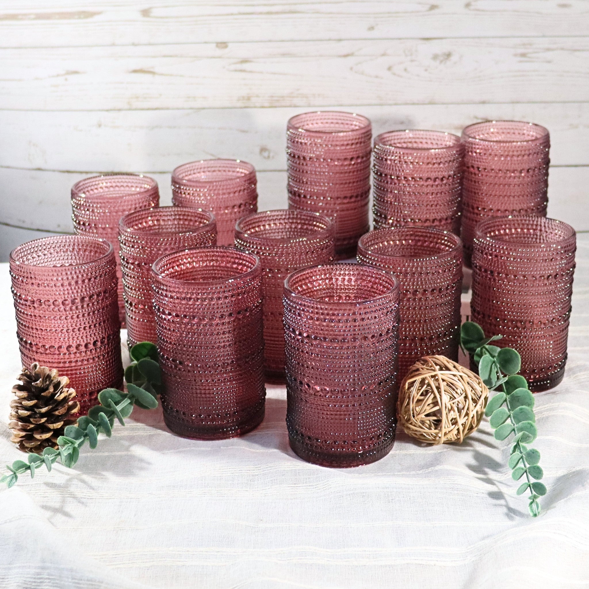 Set of pink textured glass tumblers on a white surface with decorative elements.