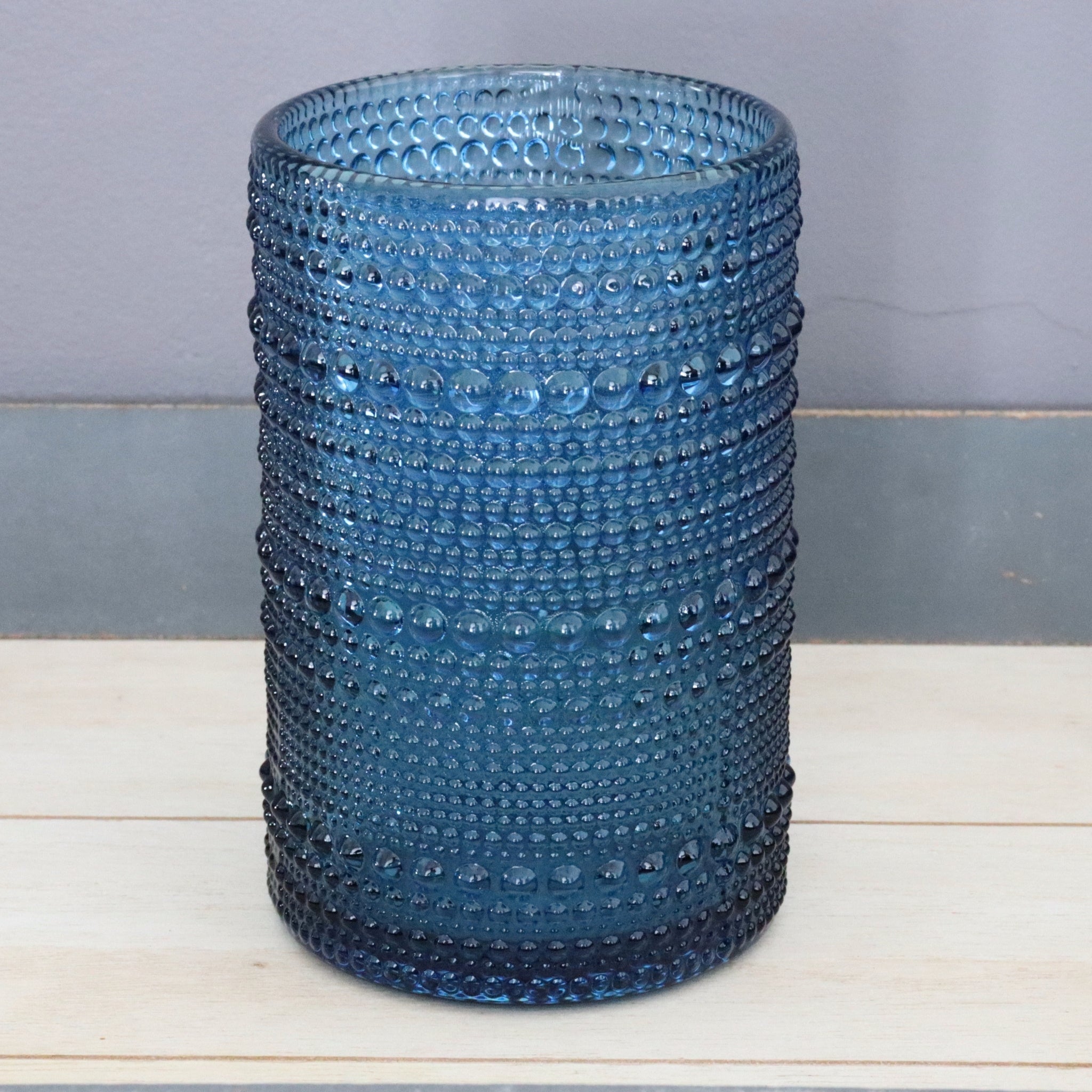 Blue hobnail glassware on a wooden surface with a grey background