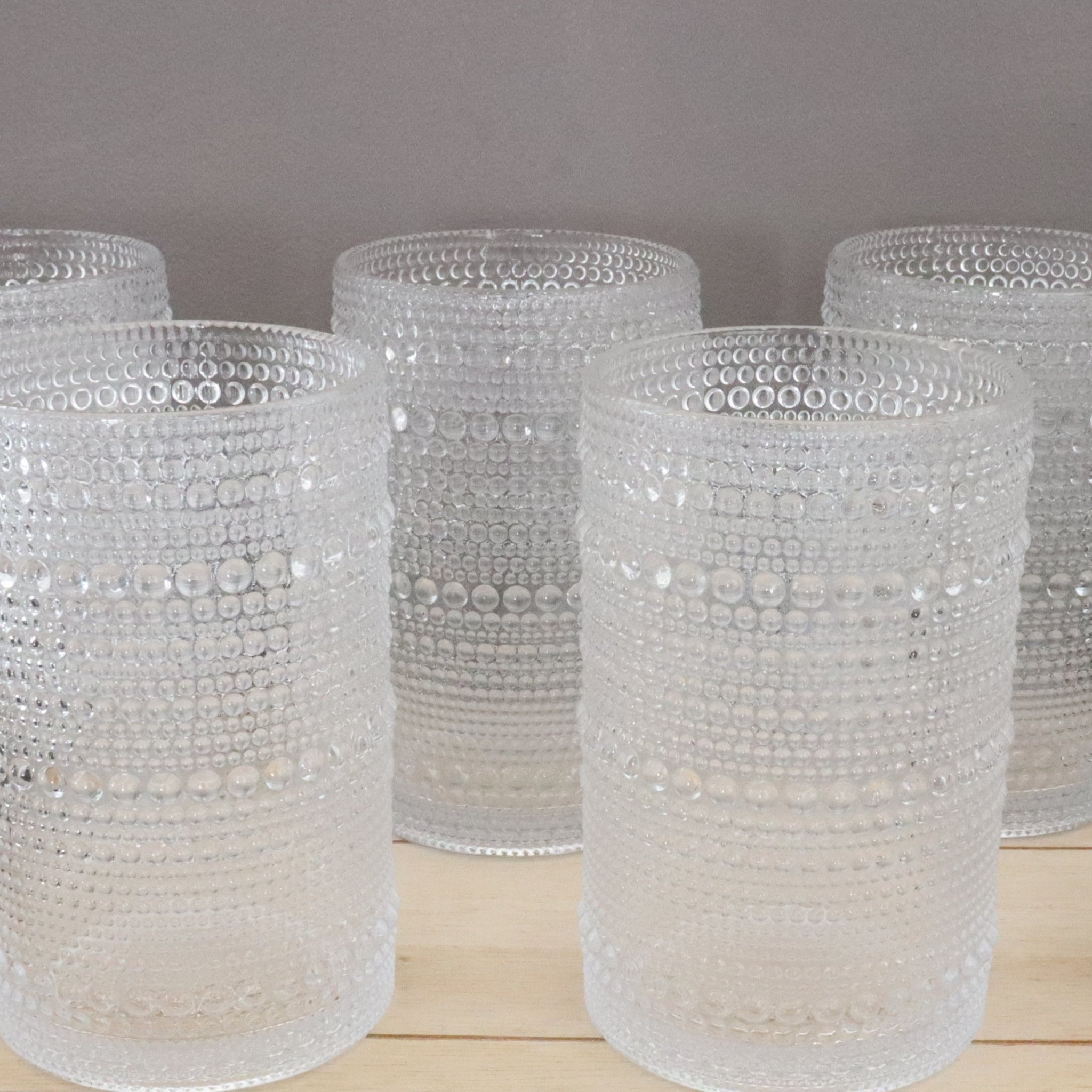 Set of clear glasses with hobnail designs on a wooden surface.