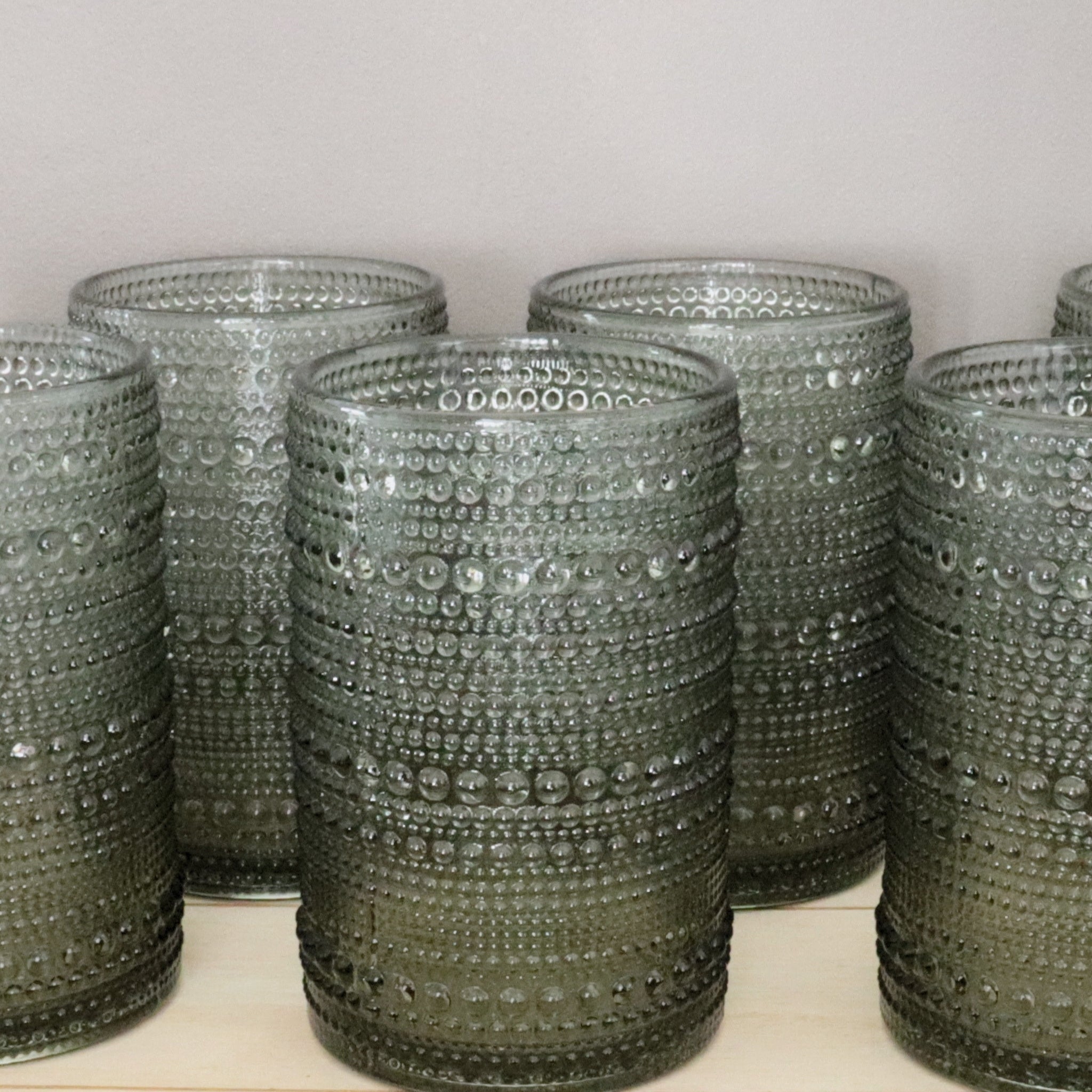 Set of hobnail glass tumblers on a light surface with a neutral background