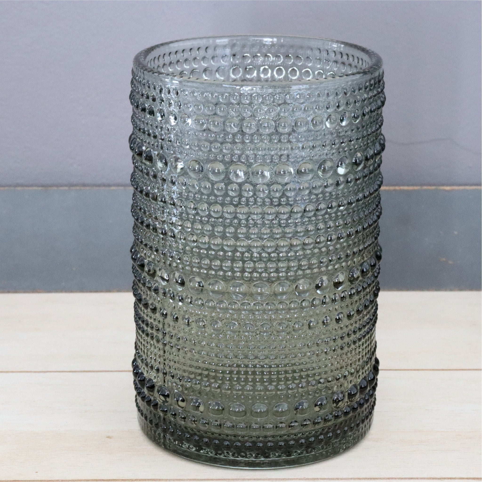 Beaded hobnail glass with textured design on a wooden surface