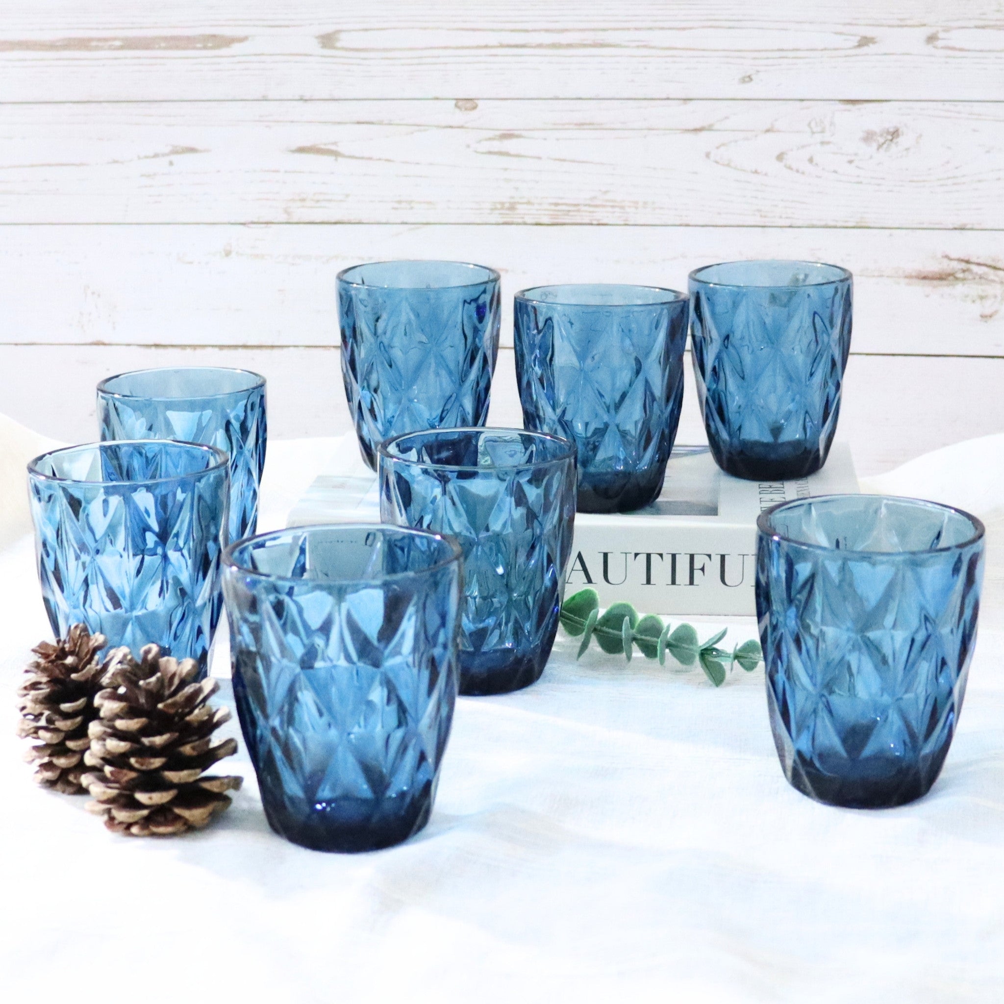 Set of blue glass tumblers on a white surface with a wooden background