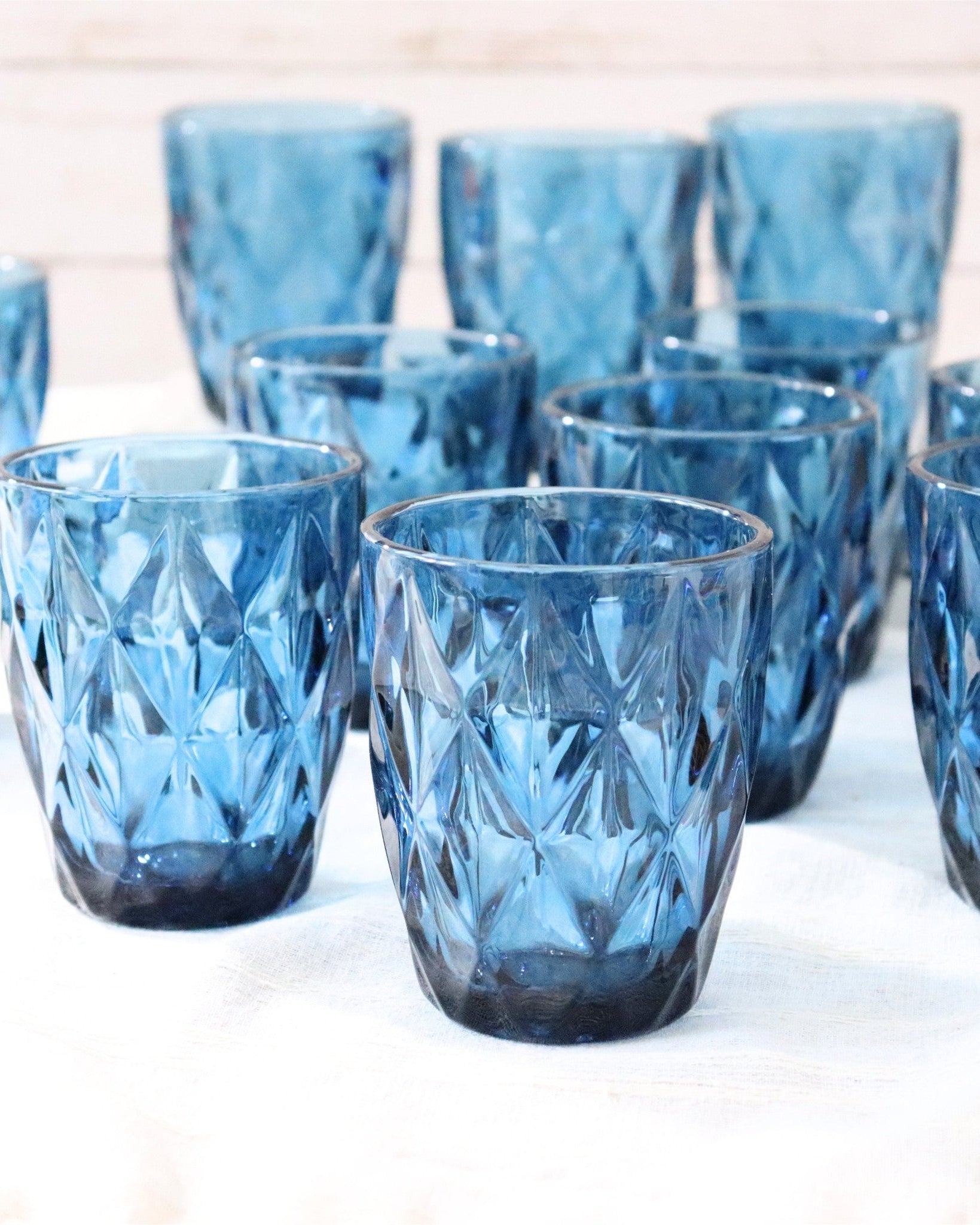 Set of blue glass tumblers with a textured design on a white surface.