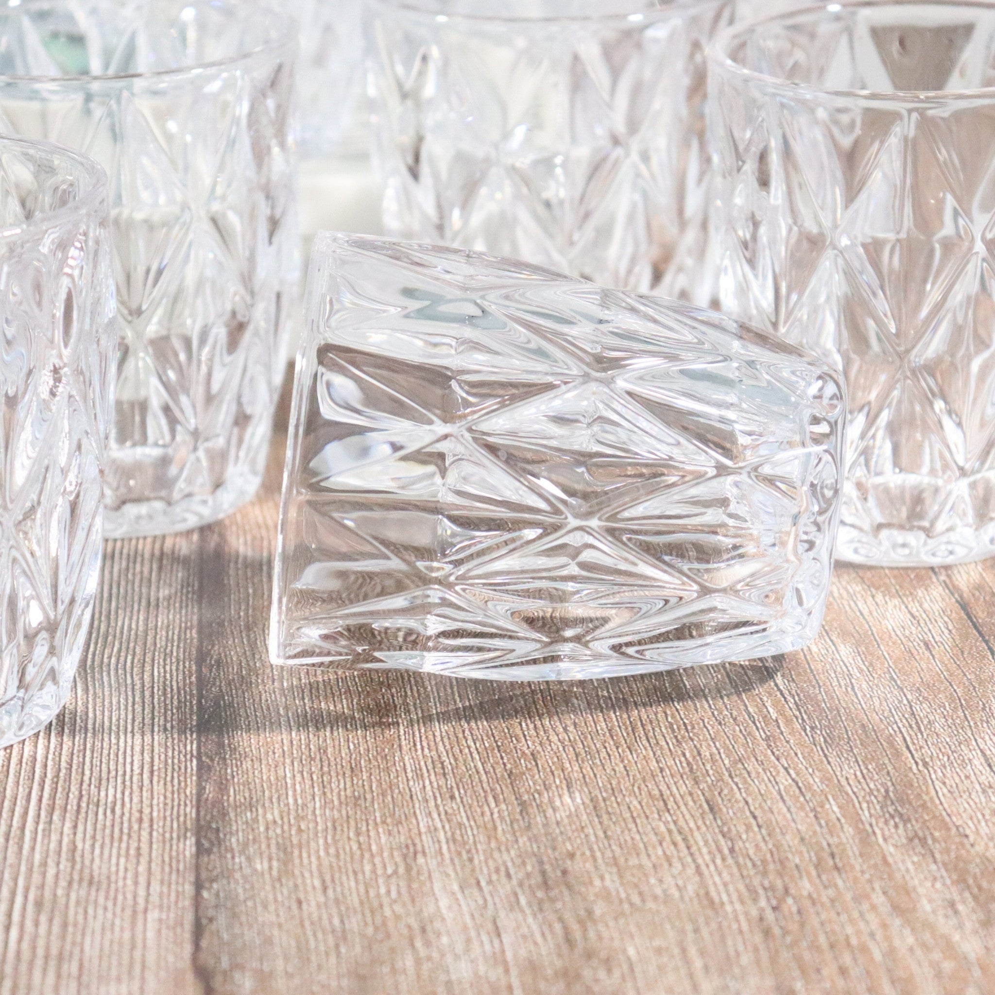 Clear glass tumblers with diamond pattern on a wooden surface