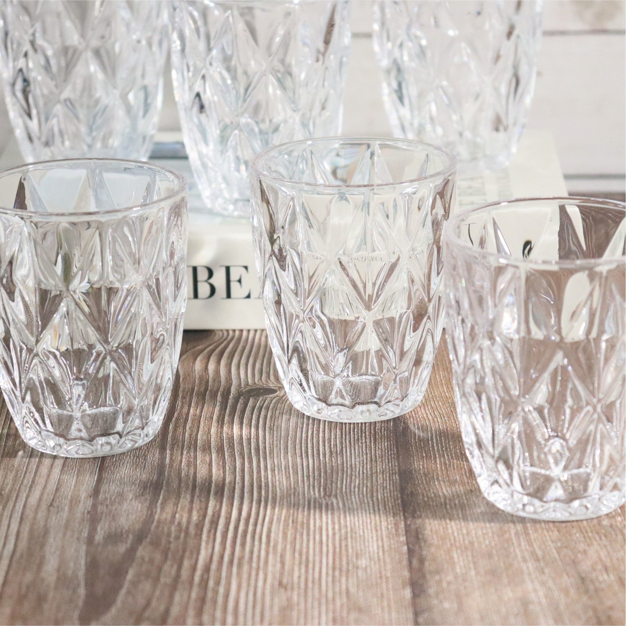 Set of clear glass tumblers with diamond pattern on a wooden surface