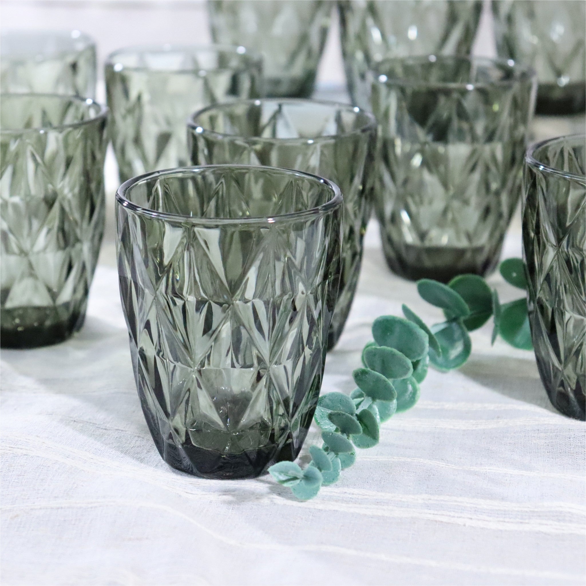 Set of smoked glass tumblers with geometric patterns on a white surface.