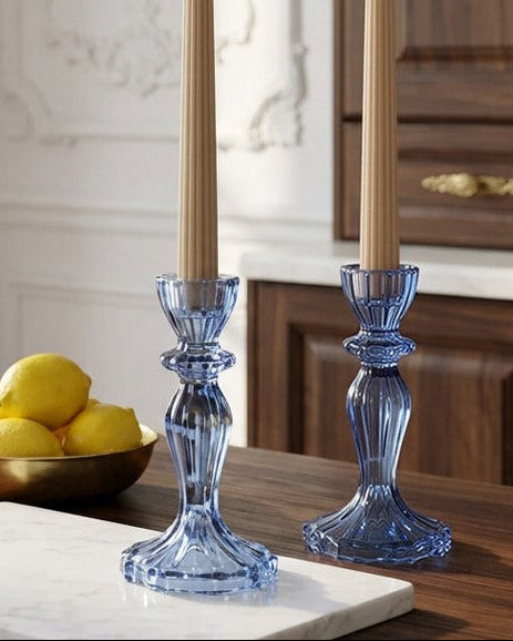 Blue candle holders on a wooden table with lemons and a cutting board.