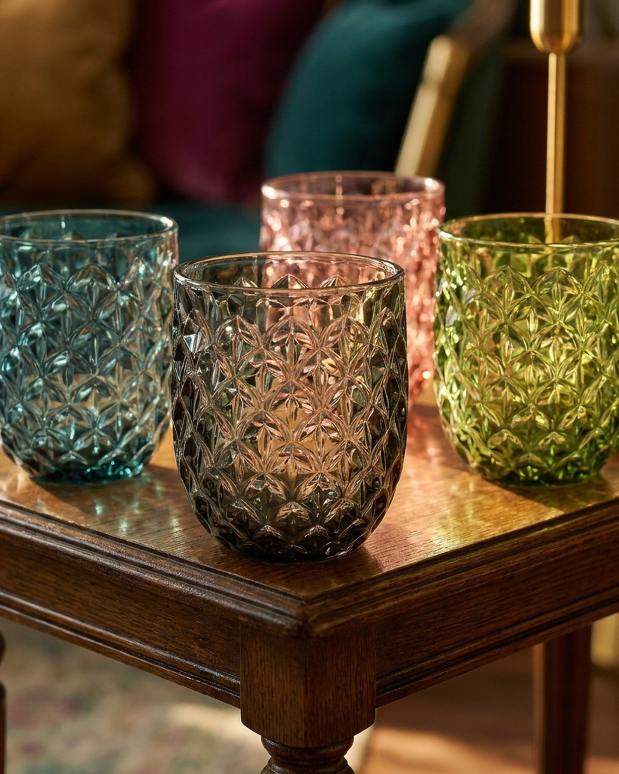 Four textured glass tumblers on a wooden table with a blurred background
