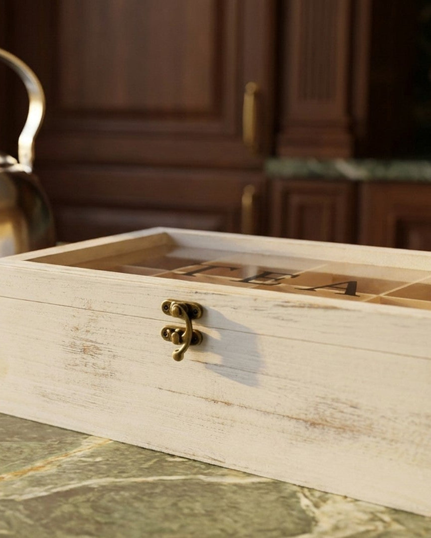 Tea storage box on a marble countertop with a box of tea bags and a kettle.