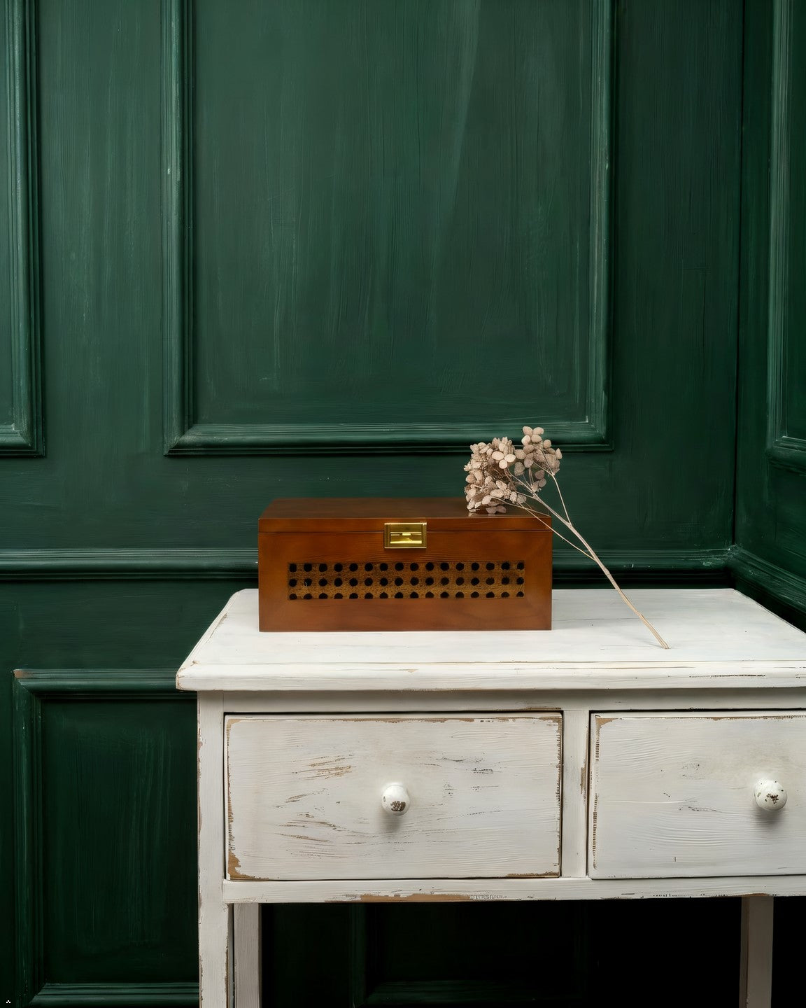 Wooden box with decorative elements on a white table against a green paneled wall