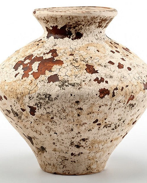 Ancient ceramic vase with brown speckles on a white background