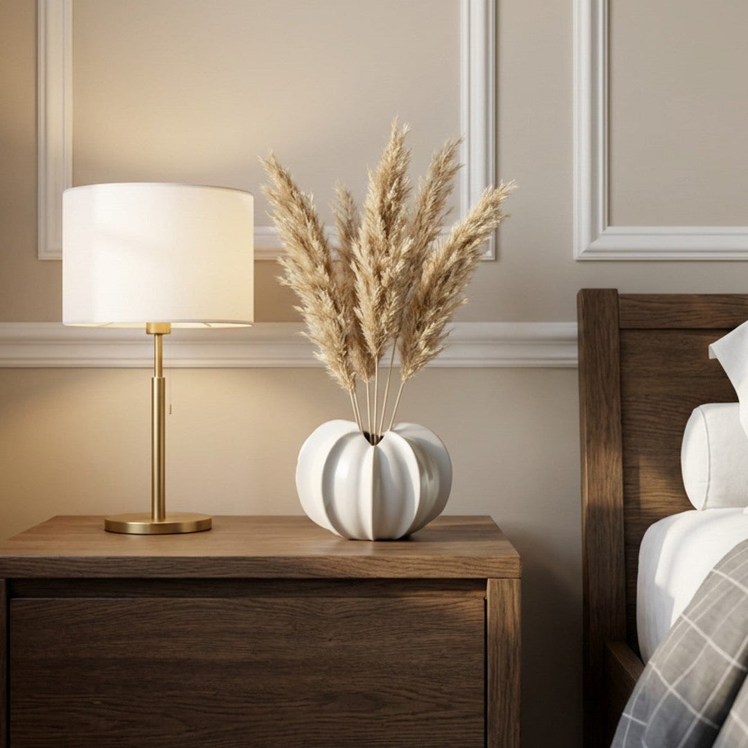 Bedroom with wooden nightstand, lamp, and decorative vase.