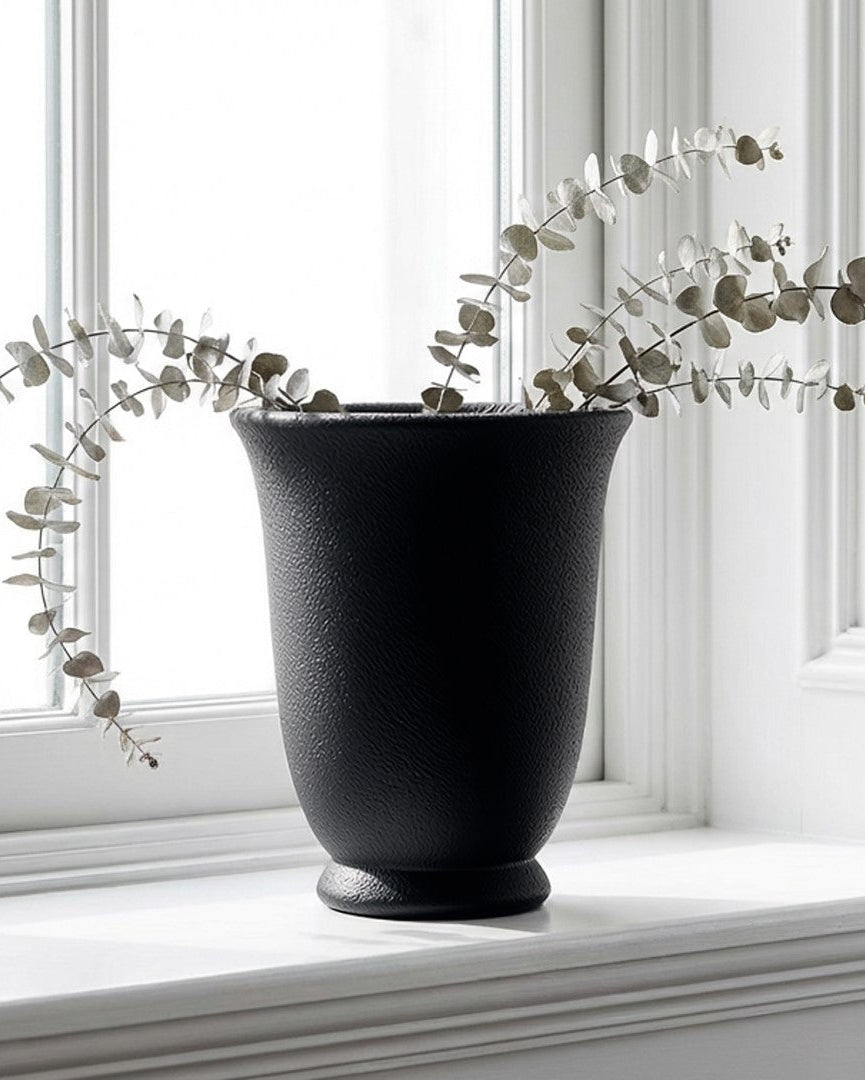 Black vase with eucalyptus on a windowsill in a bright room