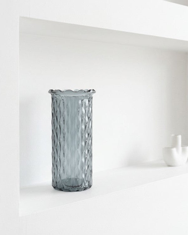 Blue textured vase on a white surface with a white wall background