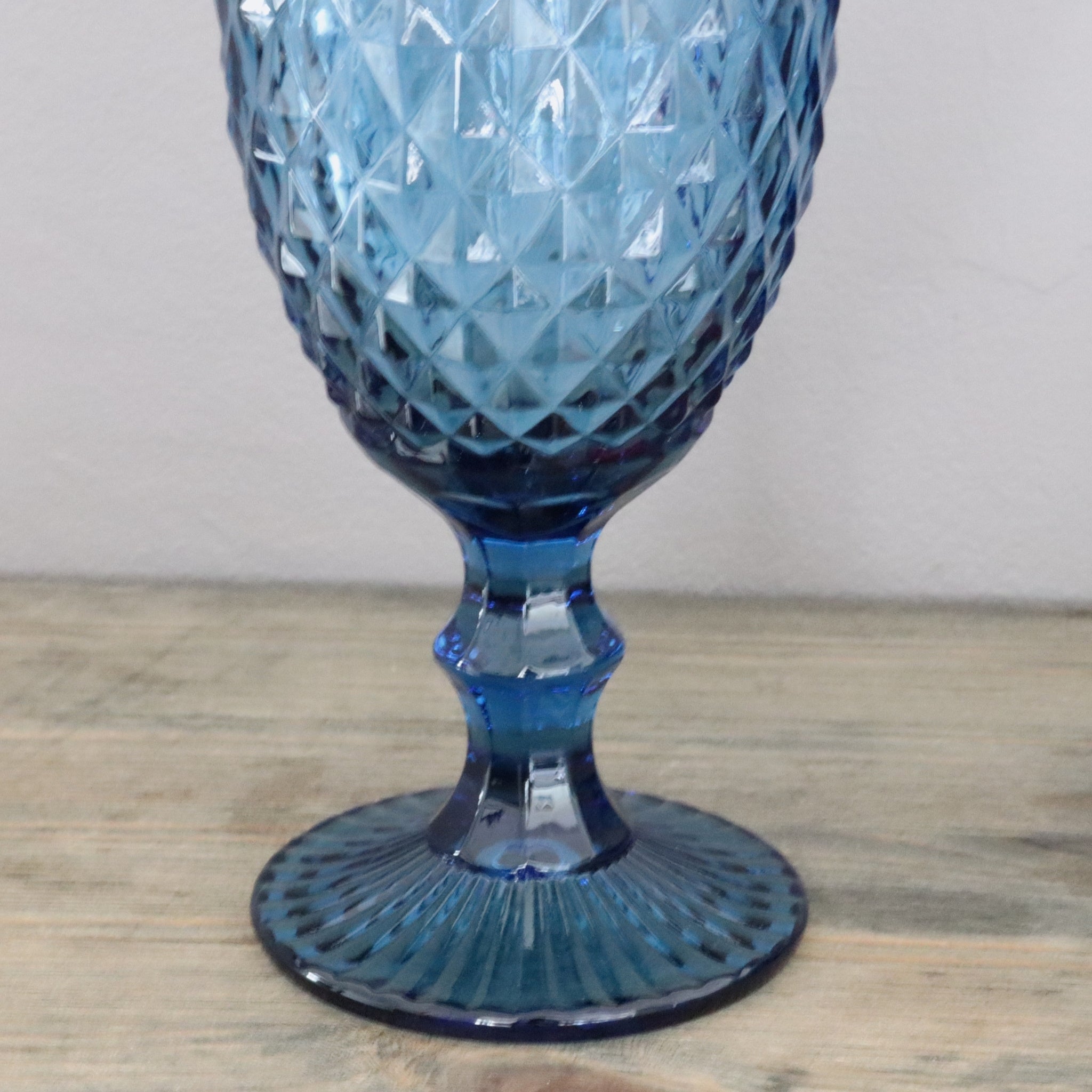 Blue glass goblet with intricate design on a wooden surface