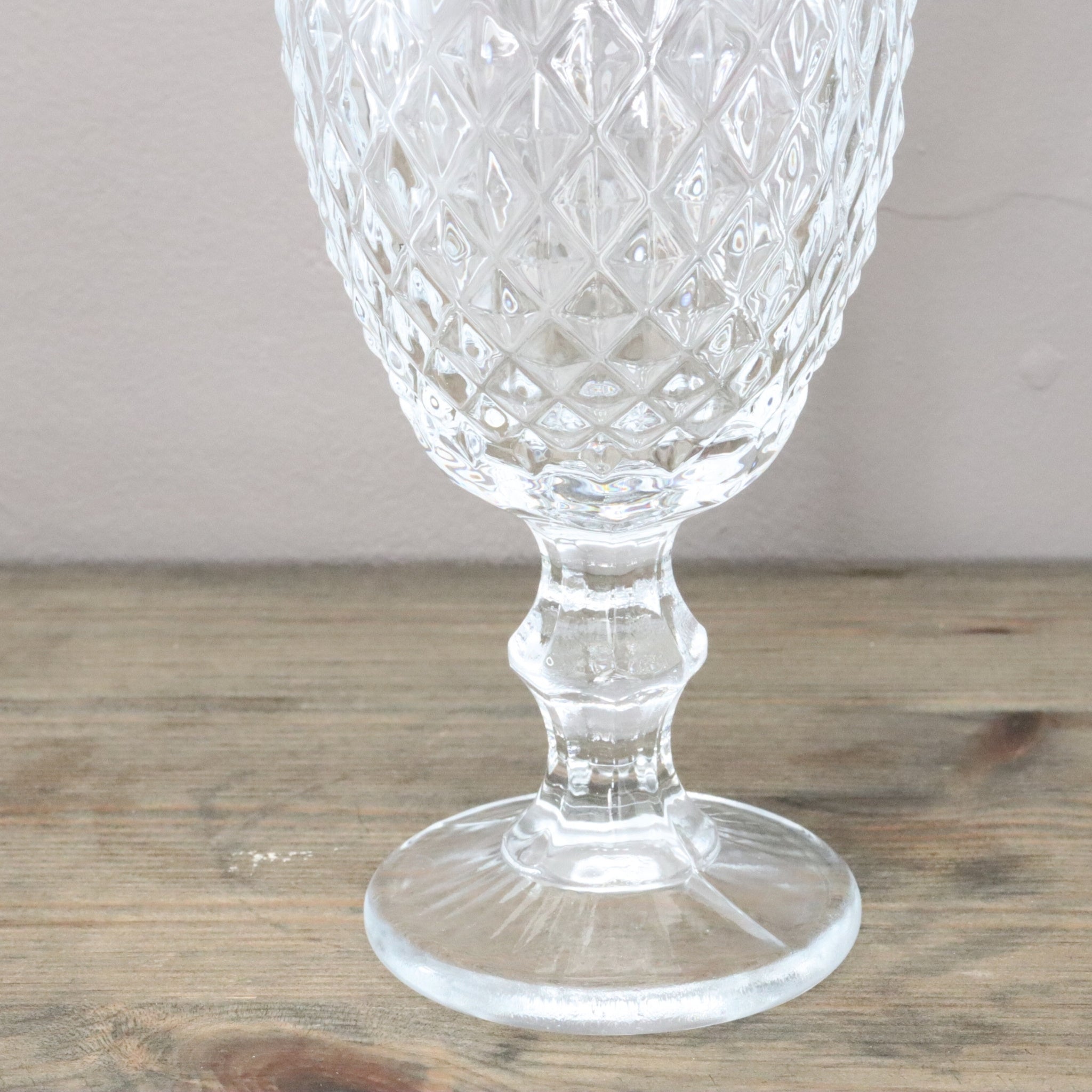 Clear glass goblet with textured design on a wooden surface