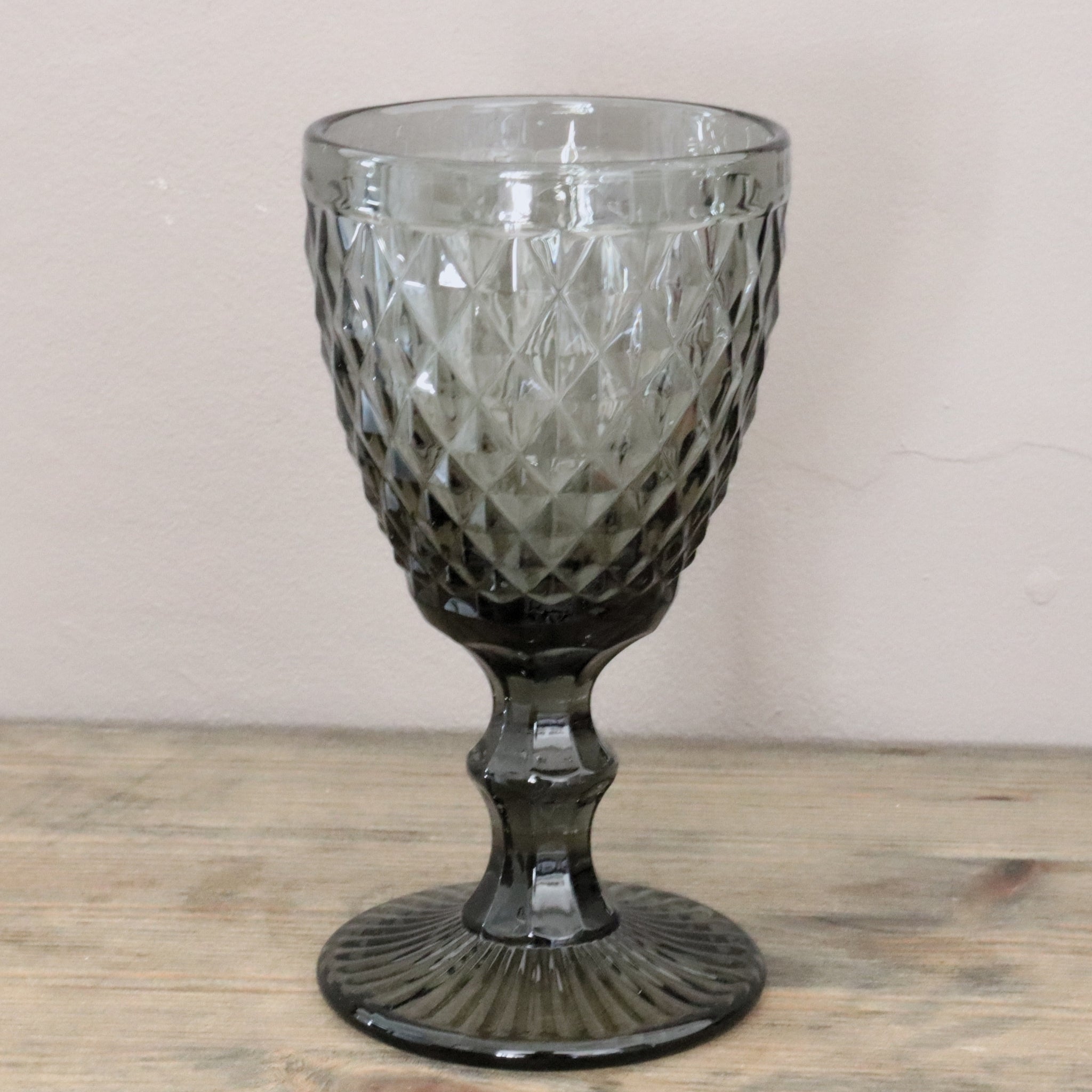 Decorative glass goblet with textured design on a wooden surface.