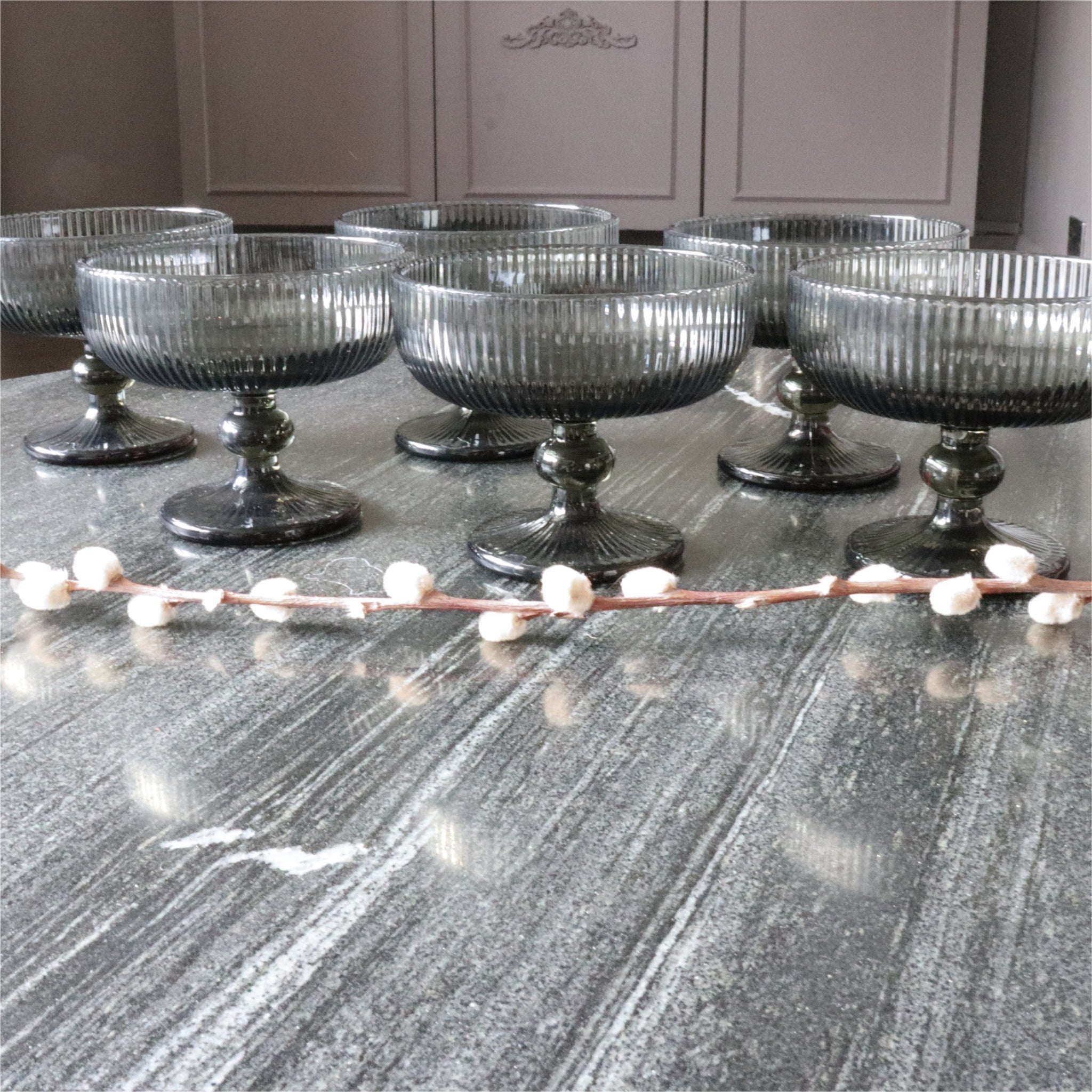 Set of six gray glass dessert bowls on a marble surface with decorative elements.