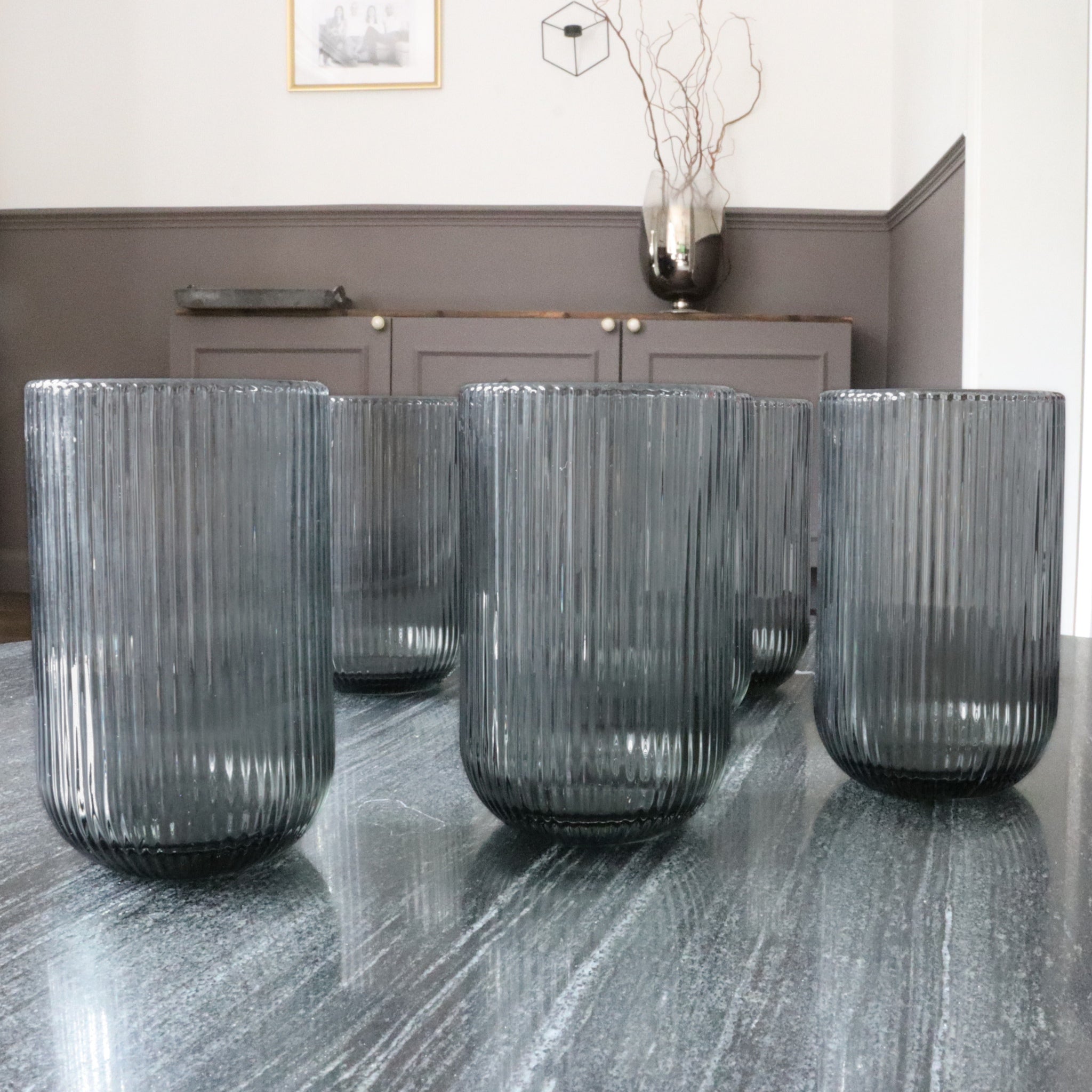 Set of ribbed glass tumblers on a reflective surface with a neutral background