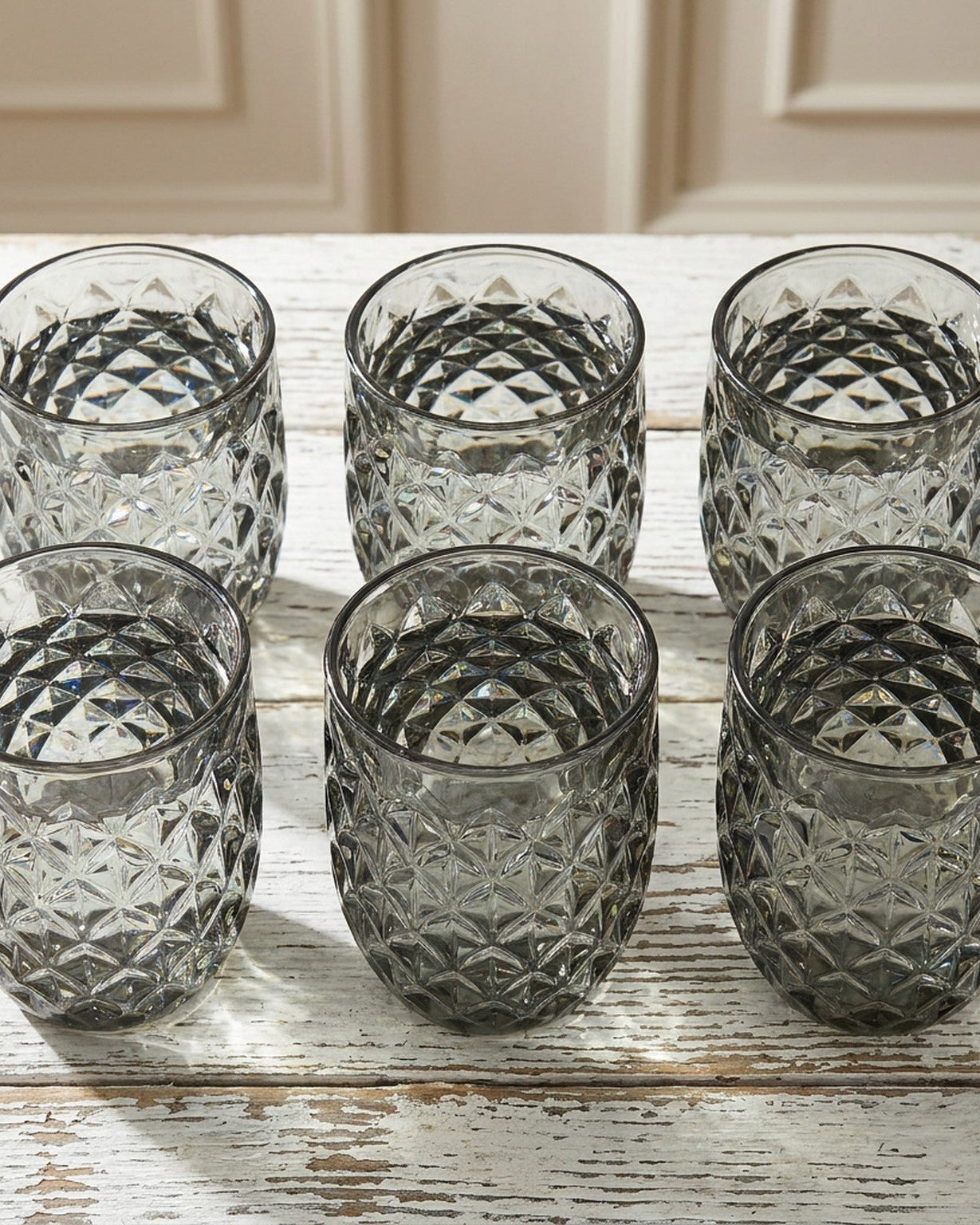 Set of four textured glass tumblers on a light surface with a neutral background
