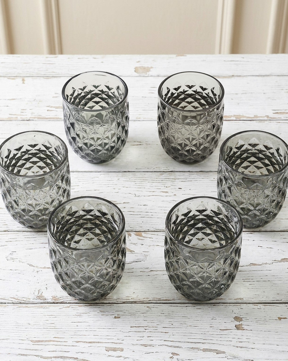 Set of textured glass tumblers on a white surface with a light gray background