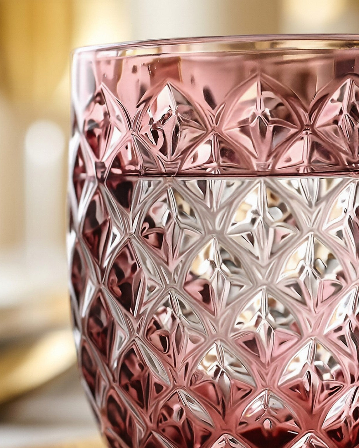 Set of purple textured glass tumblers on a light surface with a plant and shell.