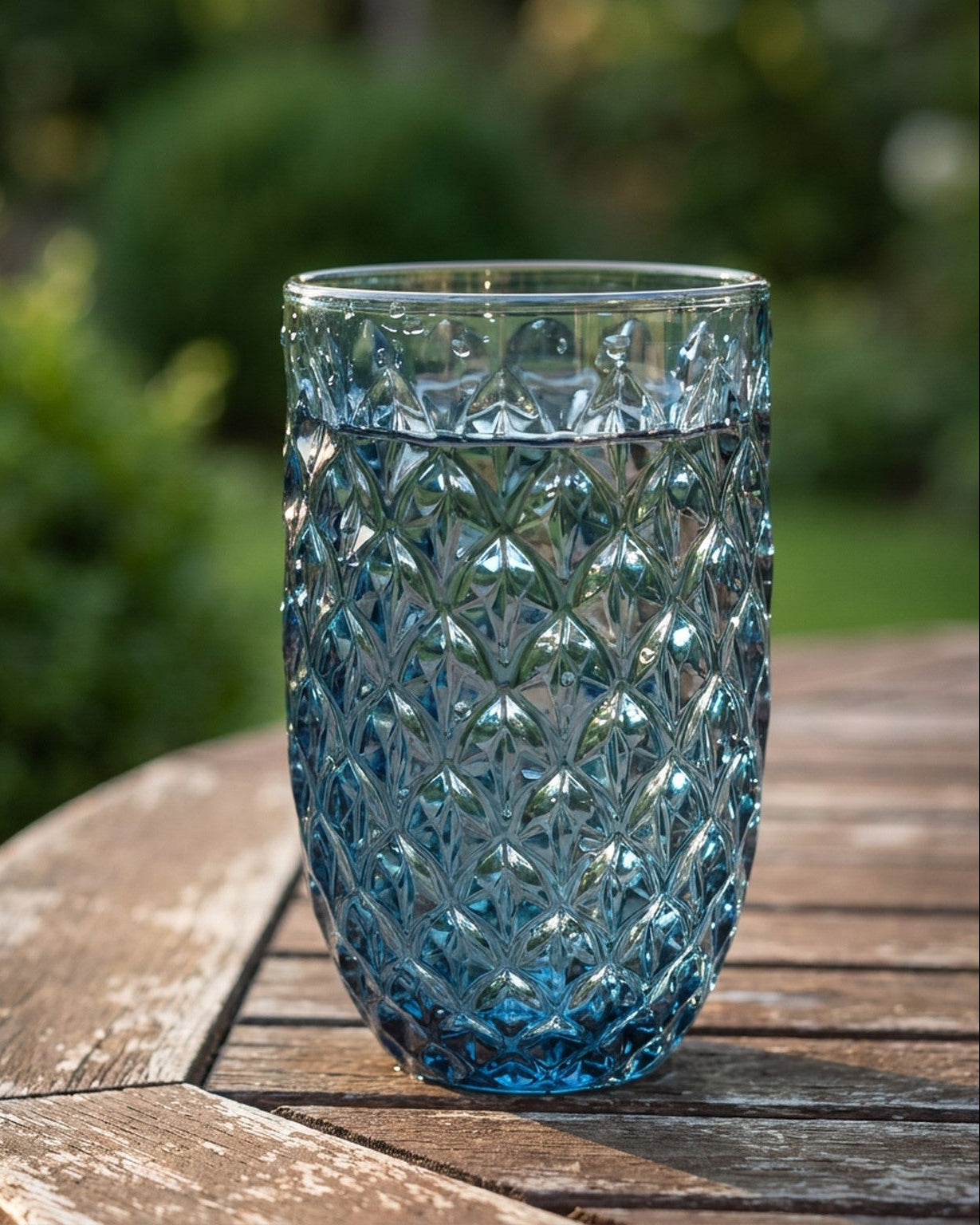 Set of blue glass tumblers with textured design on a wooden surface