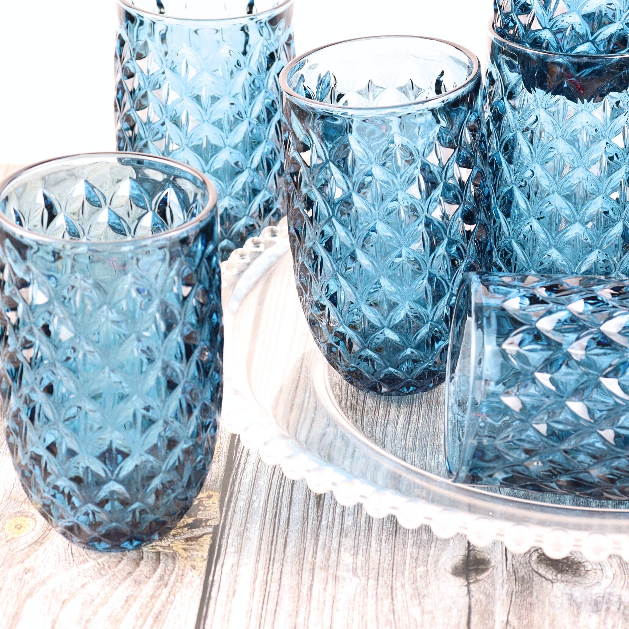 Set of blue glass tumblers with textured design on a wooden surface.