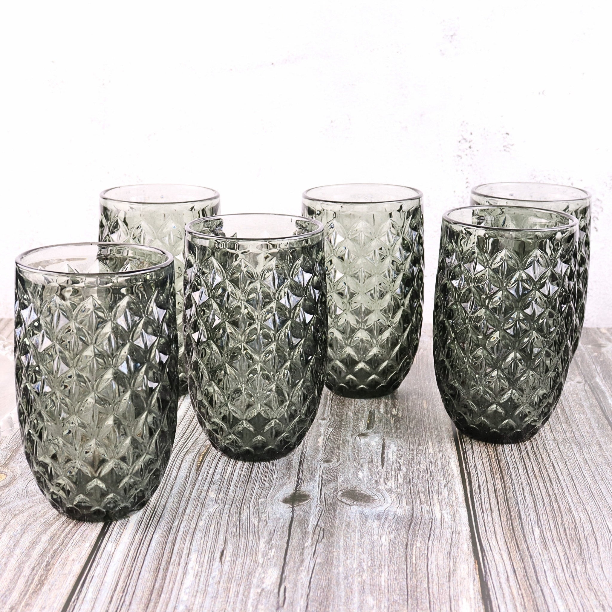 Set of six textured glass tumblers on a wooden surface