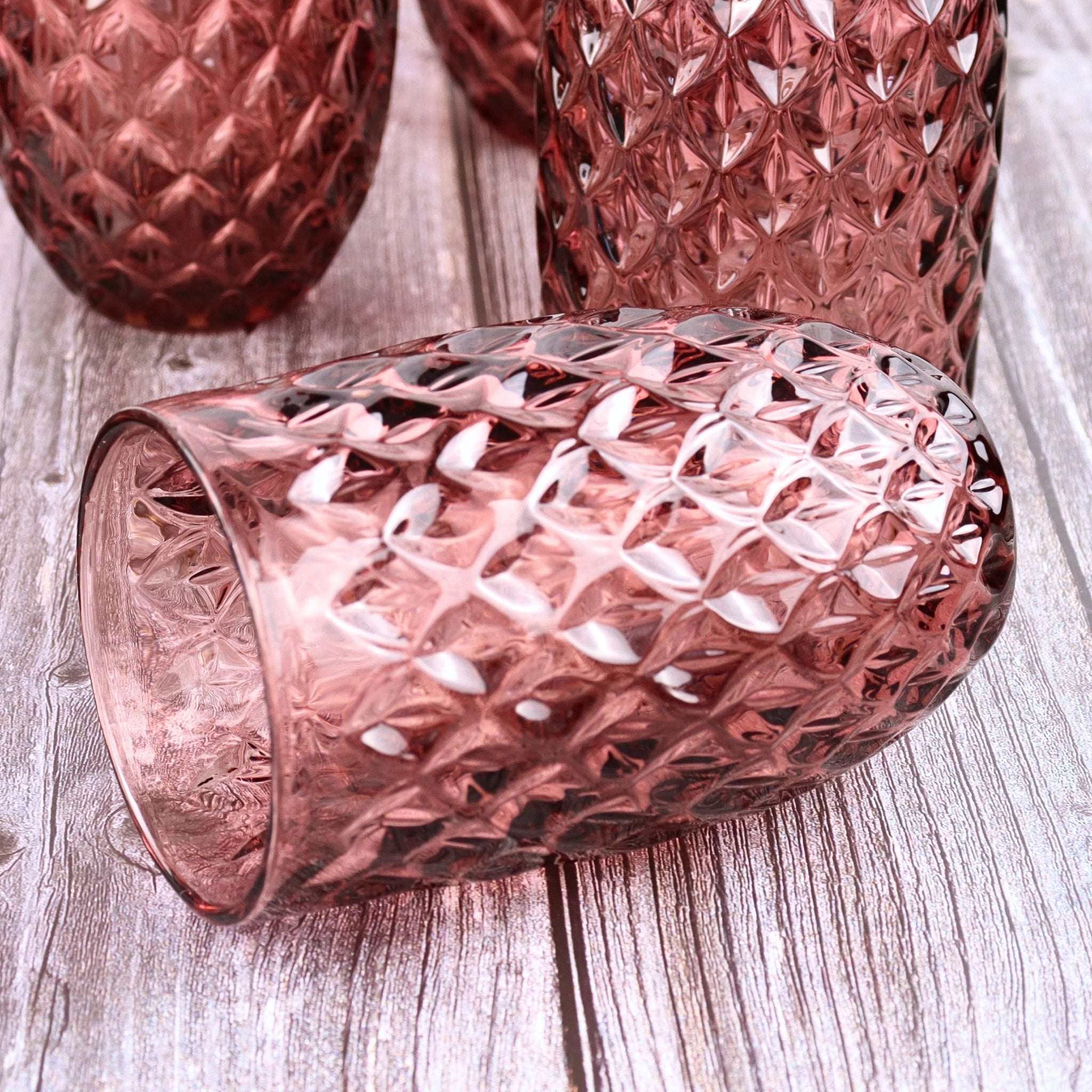 Pink textured glass tumblers on a wooden surface