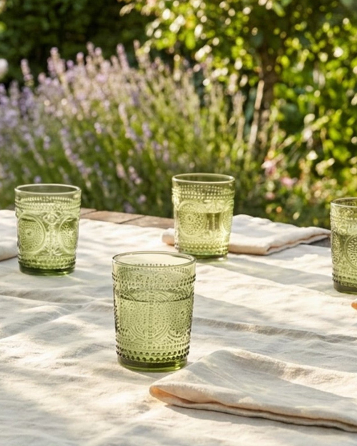 Set of green glass tumblers with textured design on a white surface.