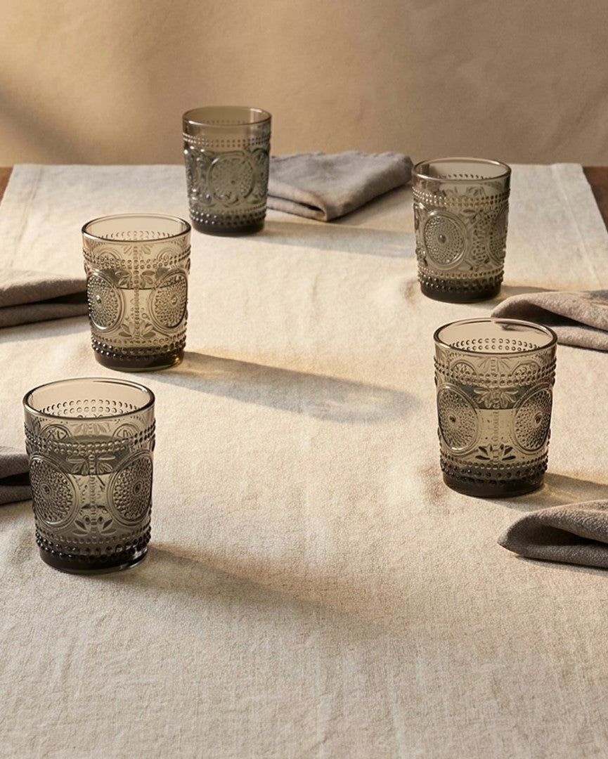 Set of green patterned glass tumblers on a white surface with a light background