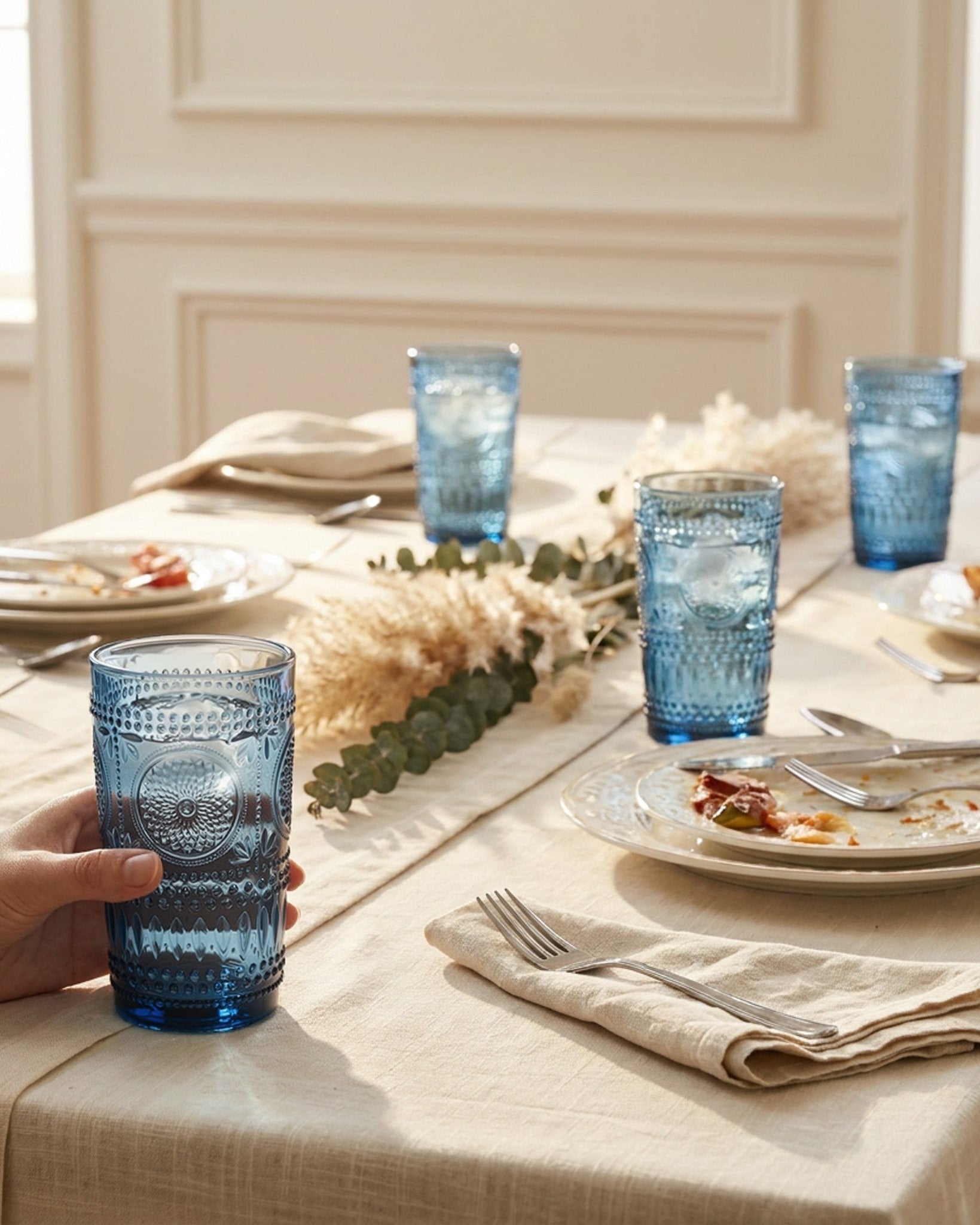 Two blue textured glass tumblers on a light surface with a white background