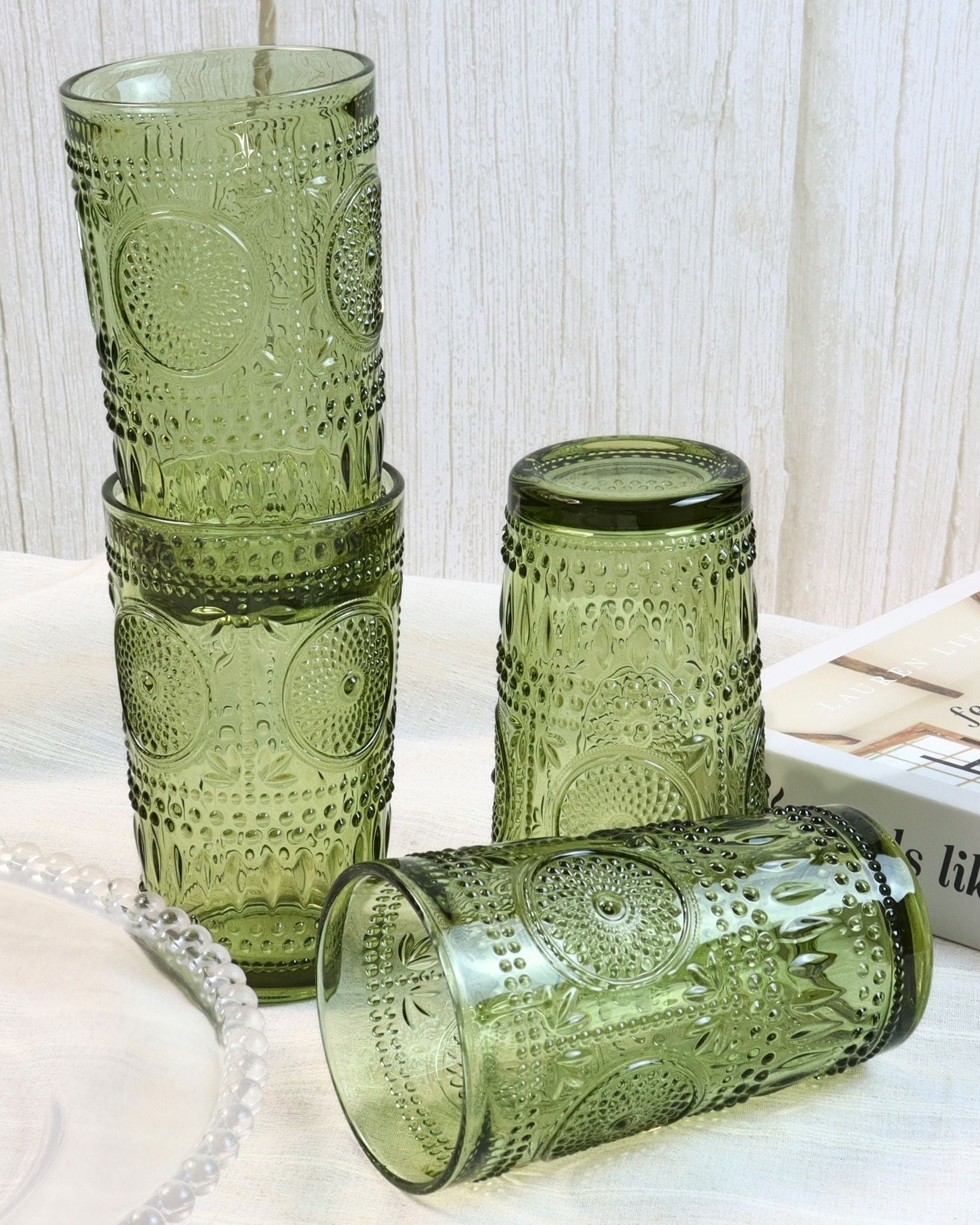 Set of green patterned glass tumblers on a light surface with a white textured background