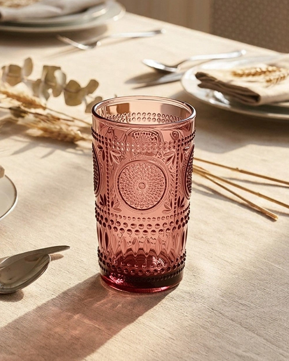 Set of purple glass tumblers with embossed designs on a light surface.