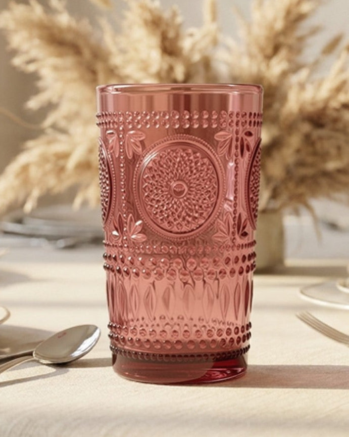 Set of six purple glass tumblers with embossed designs on a white surface.