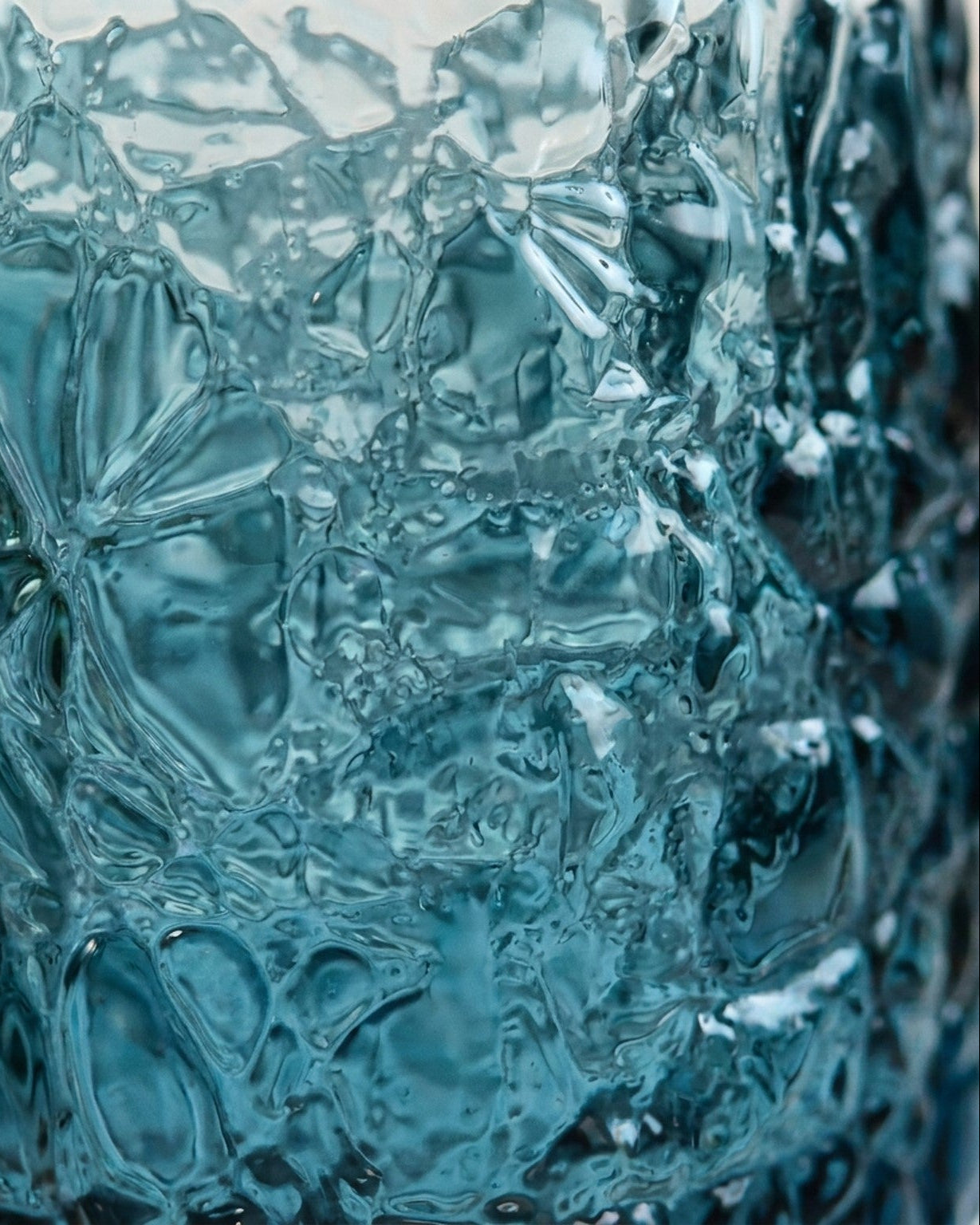 Set of blue textured glasses on a marble surface with a wooden background
