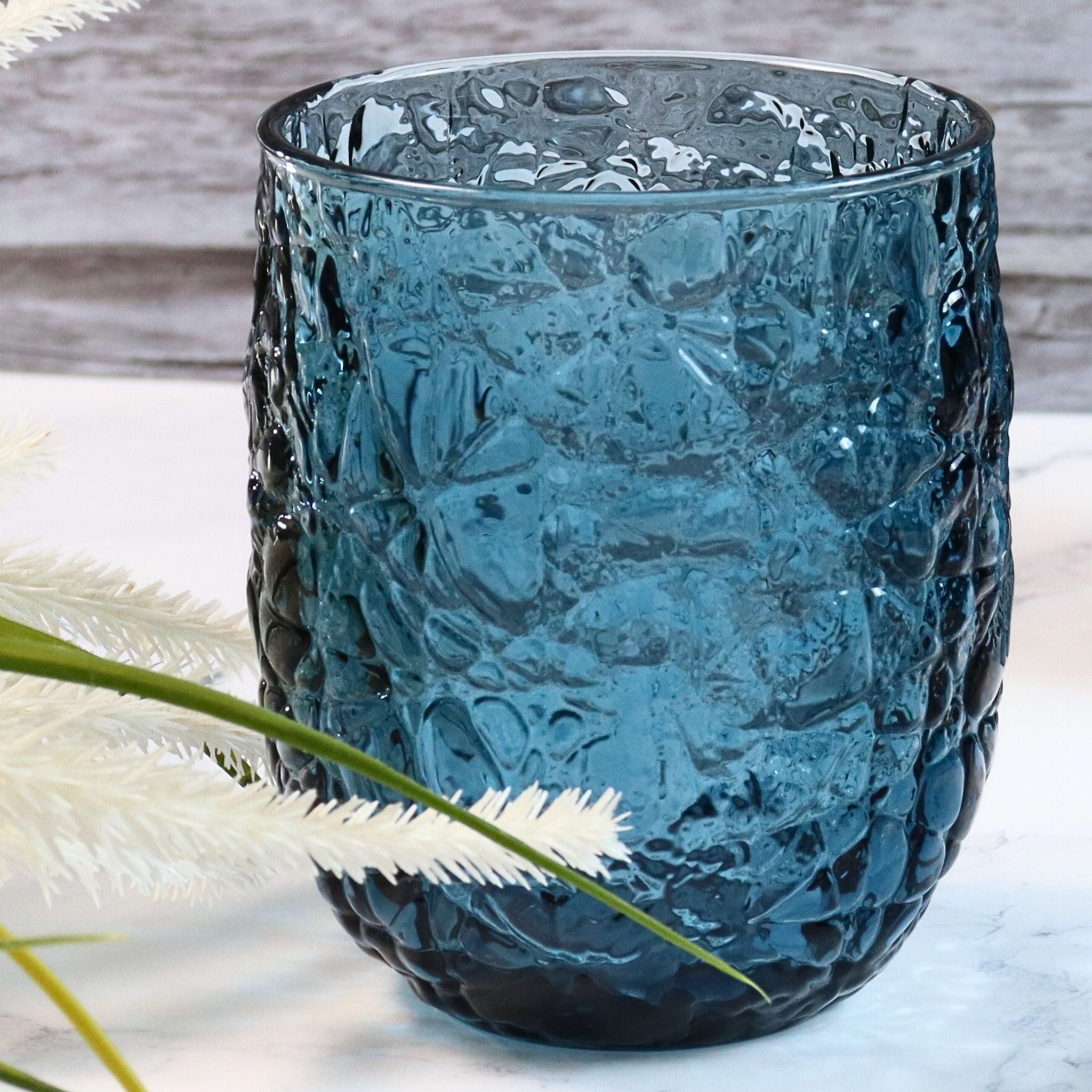 Blue textured glass vase on a light surface with a blurred natural background