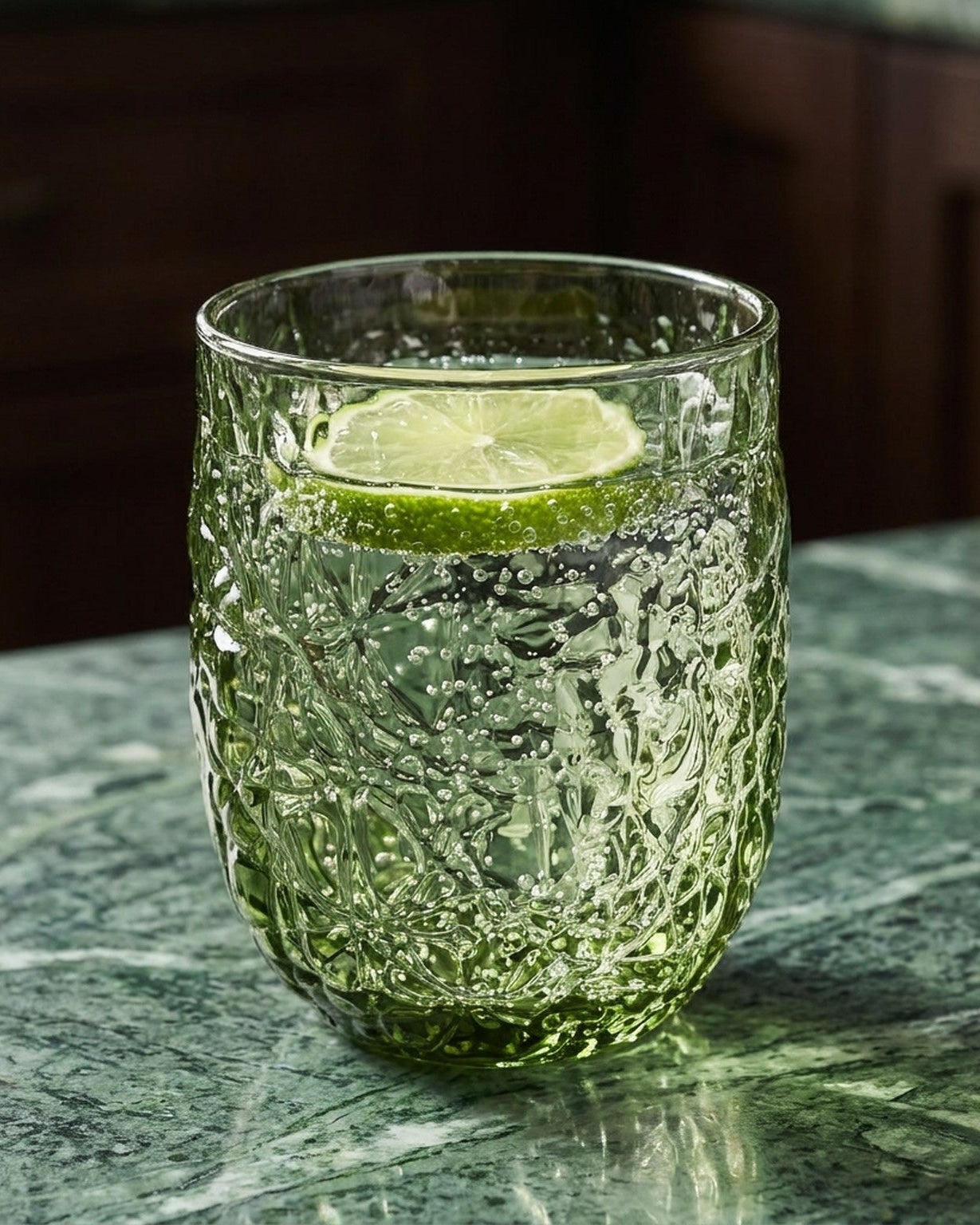 Set of green textured glass tumblers on a marble surface with a light gray background