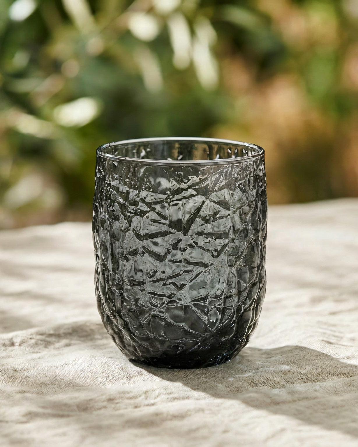 Four textured gray glasses on a marble surface with decorative elements.