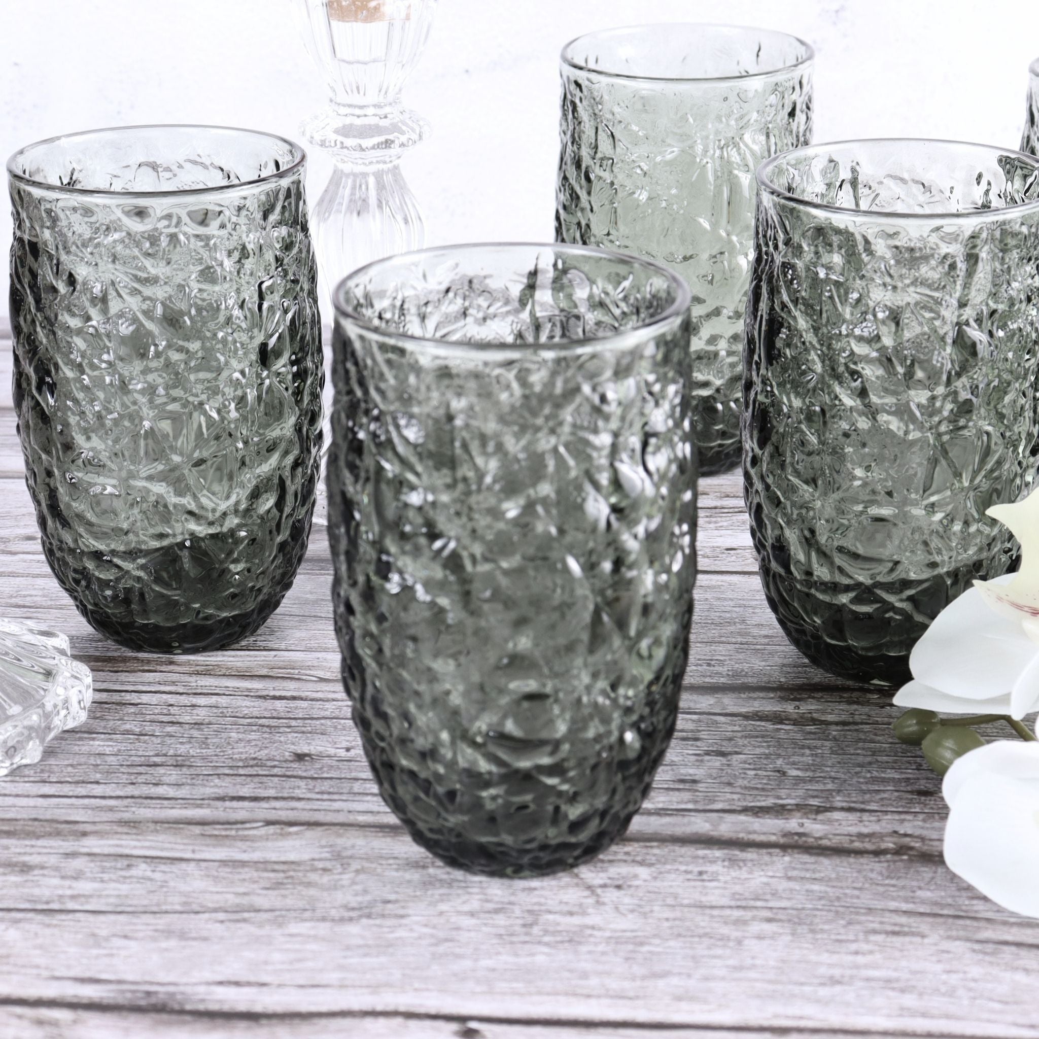 Set of textured glass tumblers on a wooden surface with a blurred background
