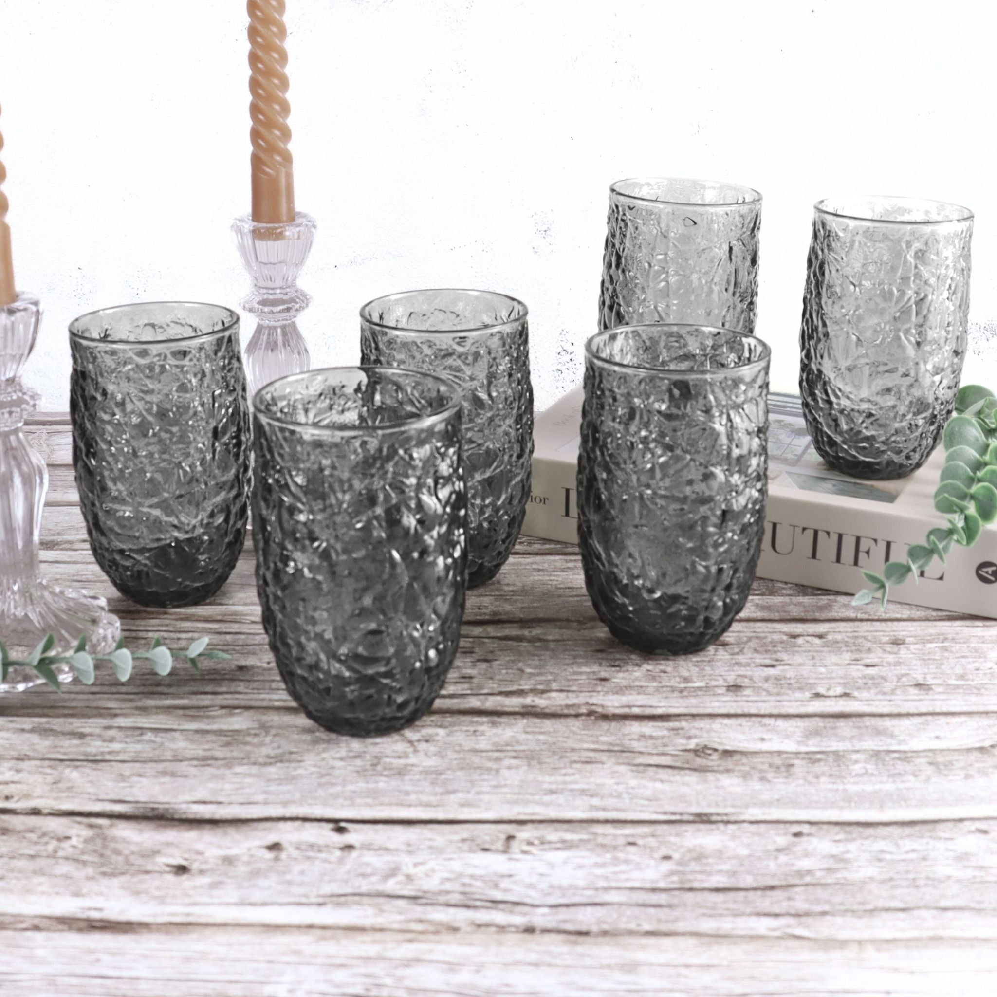 Set of textured gray glass tumblers on a wooden surface with a white background