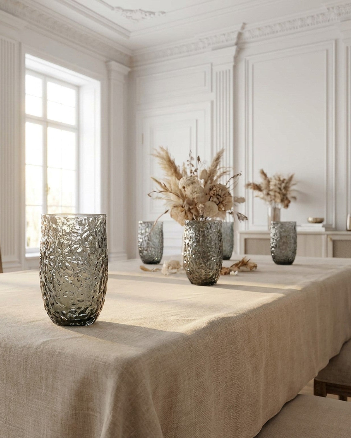 Set of four textured glass tumblers on a wooden surface with a magazine underneath.