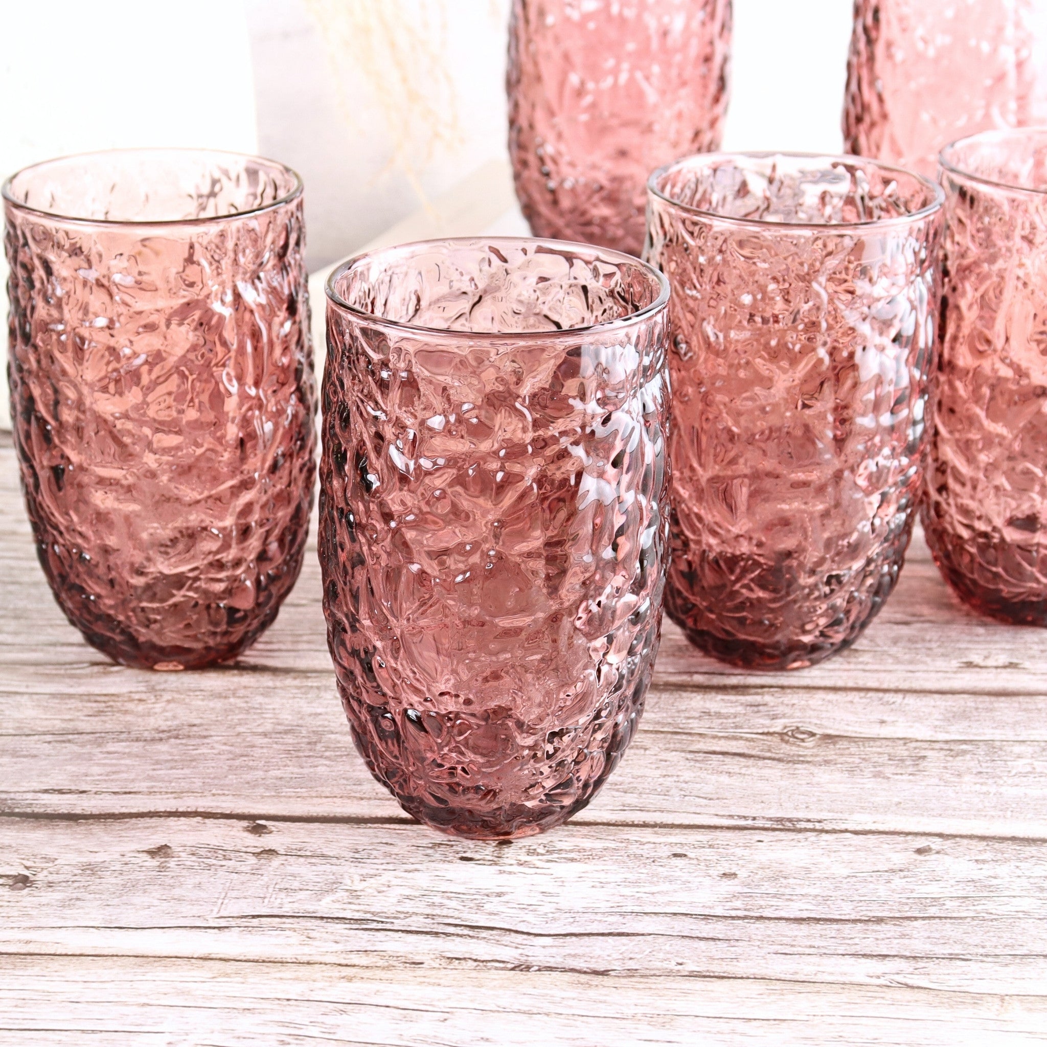 Set of pink textured glass tumblers on a wooden surface