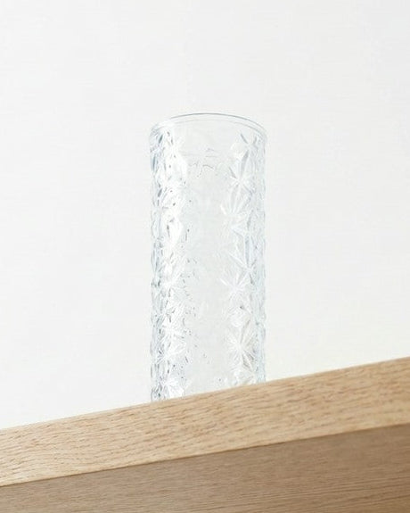 Clear glass vase with diamond cut pattern on a wooden surface